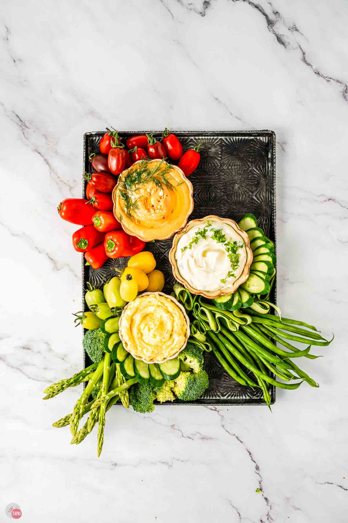 Fresh vegetable platter with three bowls of dips