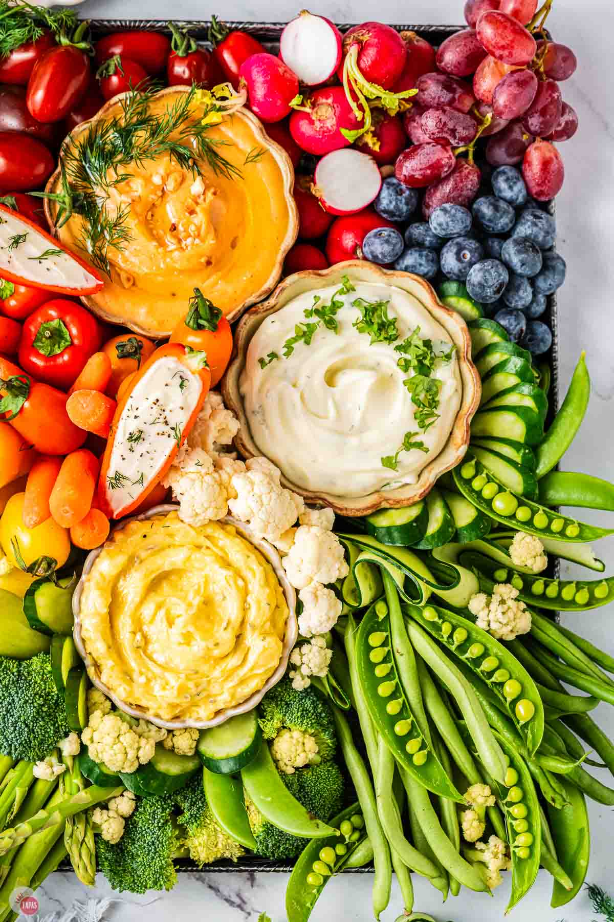close up of dips and raw vegetables on a platter