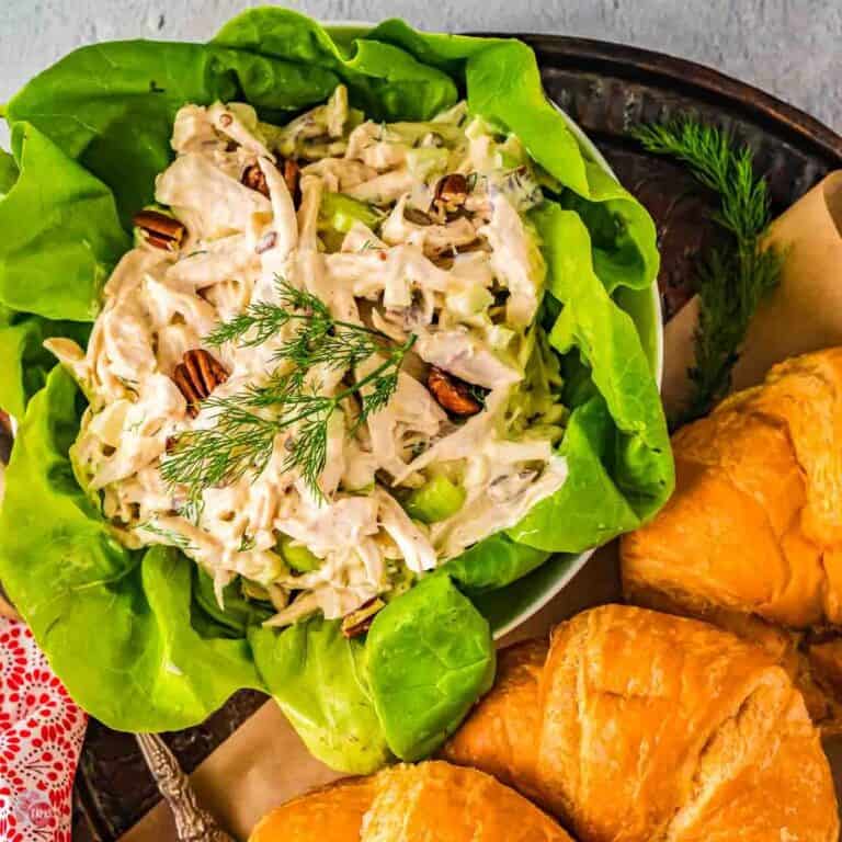 lettuce bowl filled with chicken salad surrounded by croissants