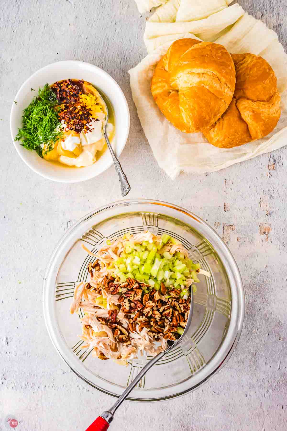 clear bowl with diced chicken, celery, and chopped pecans in it