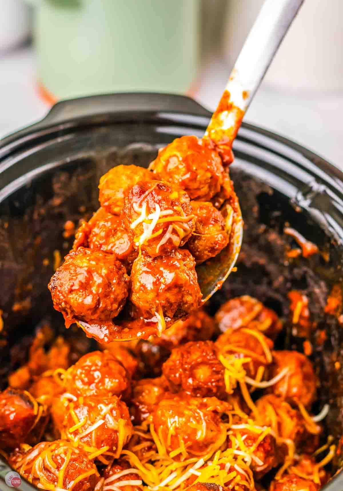 spoon of meatballs topped with shredded cheese