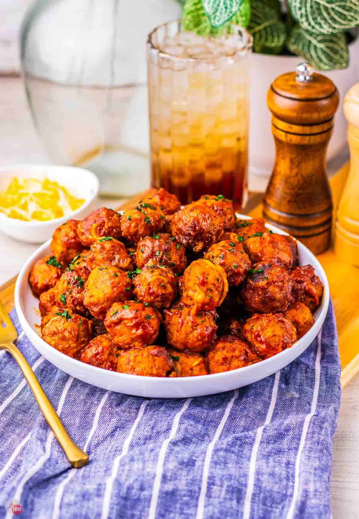 white plate with meatballs and a glass of iced tea behind it