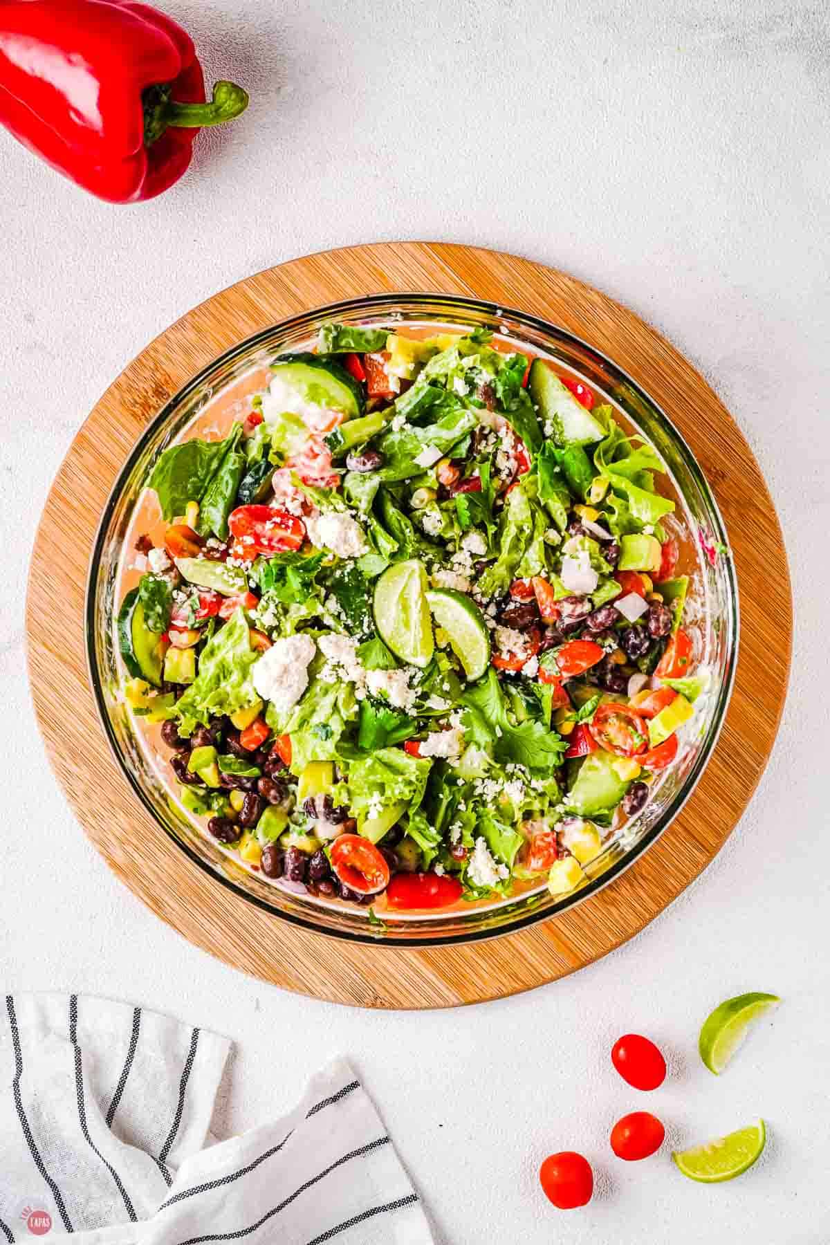 wood circle with clear bowl filled with Fiesta salad in it