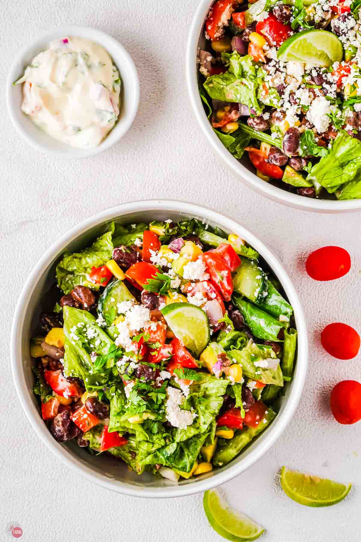 two bowls of salad with cherry tomatoes on the side