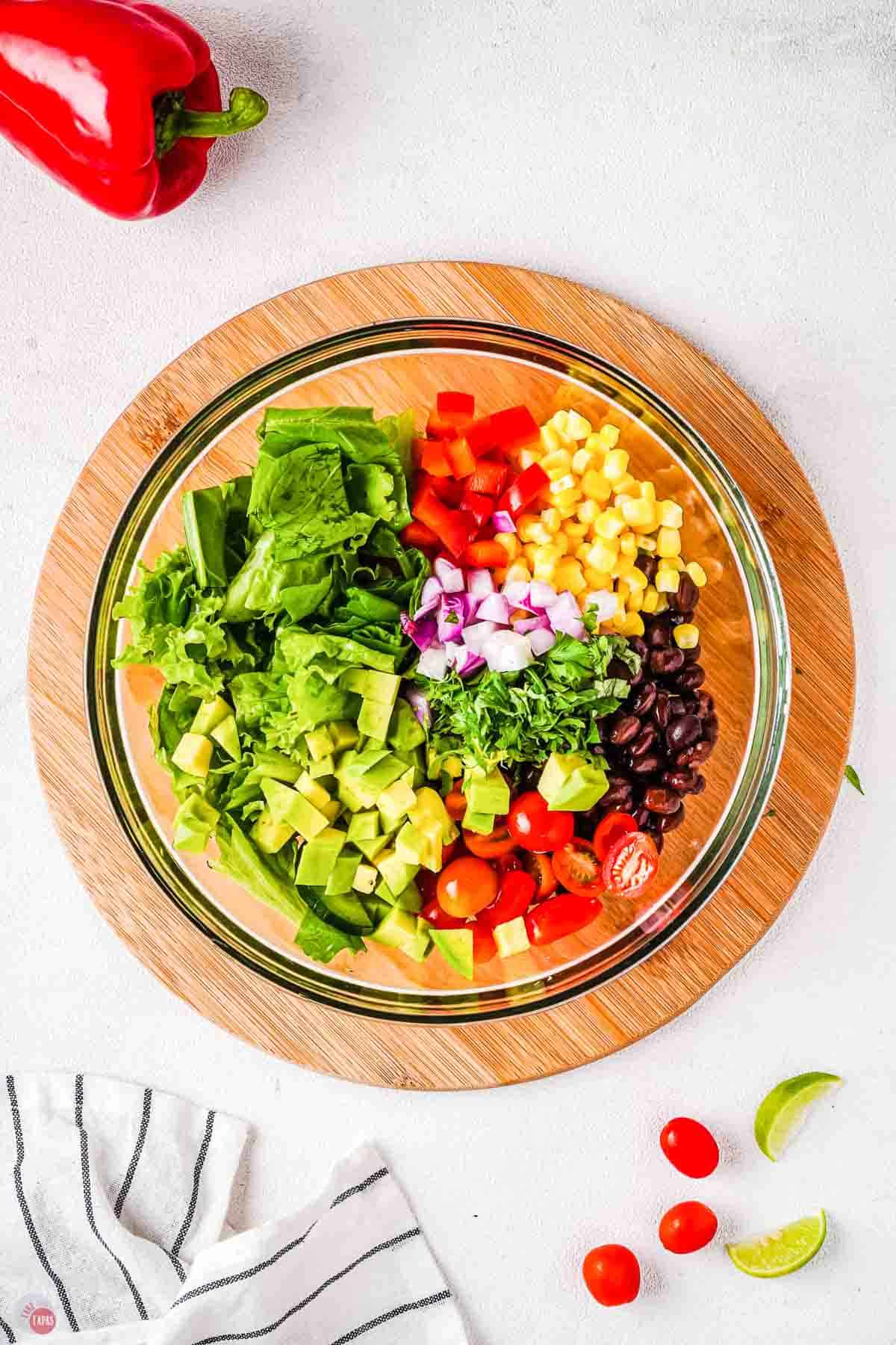 clear bowl with salad ingredients in it unmixed