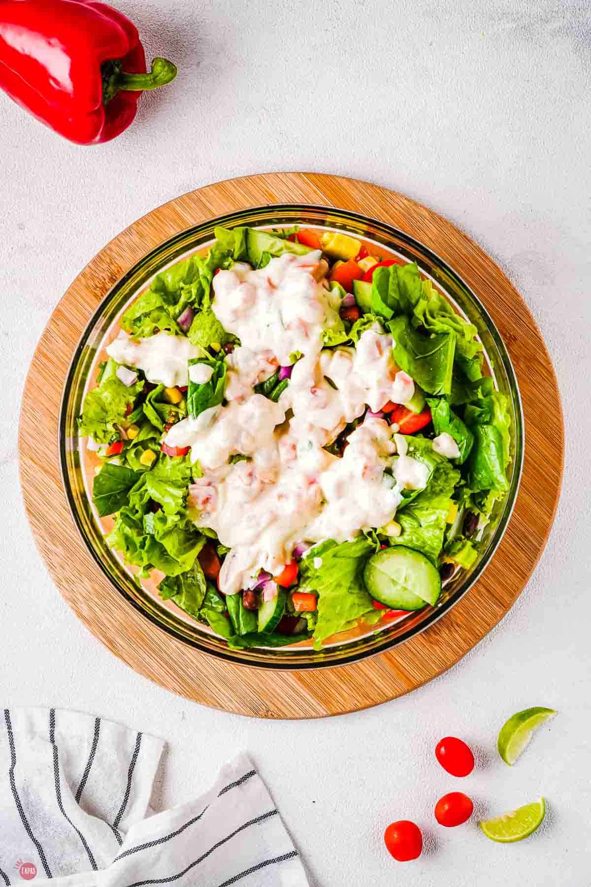 clear bowl of salad ingredients topped with a creamy dressing