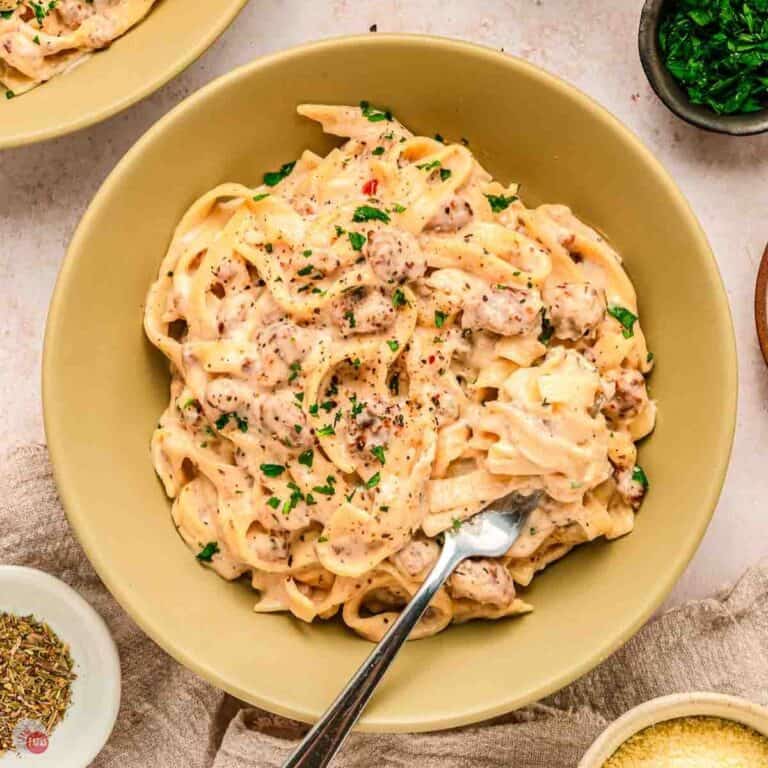yellow bowl of pasta with a fork and bowl of cheese next to it
