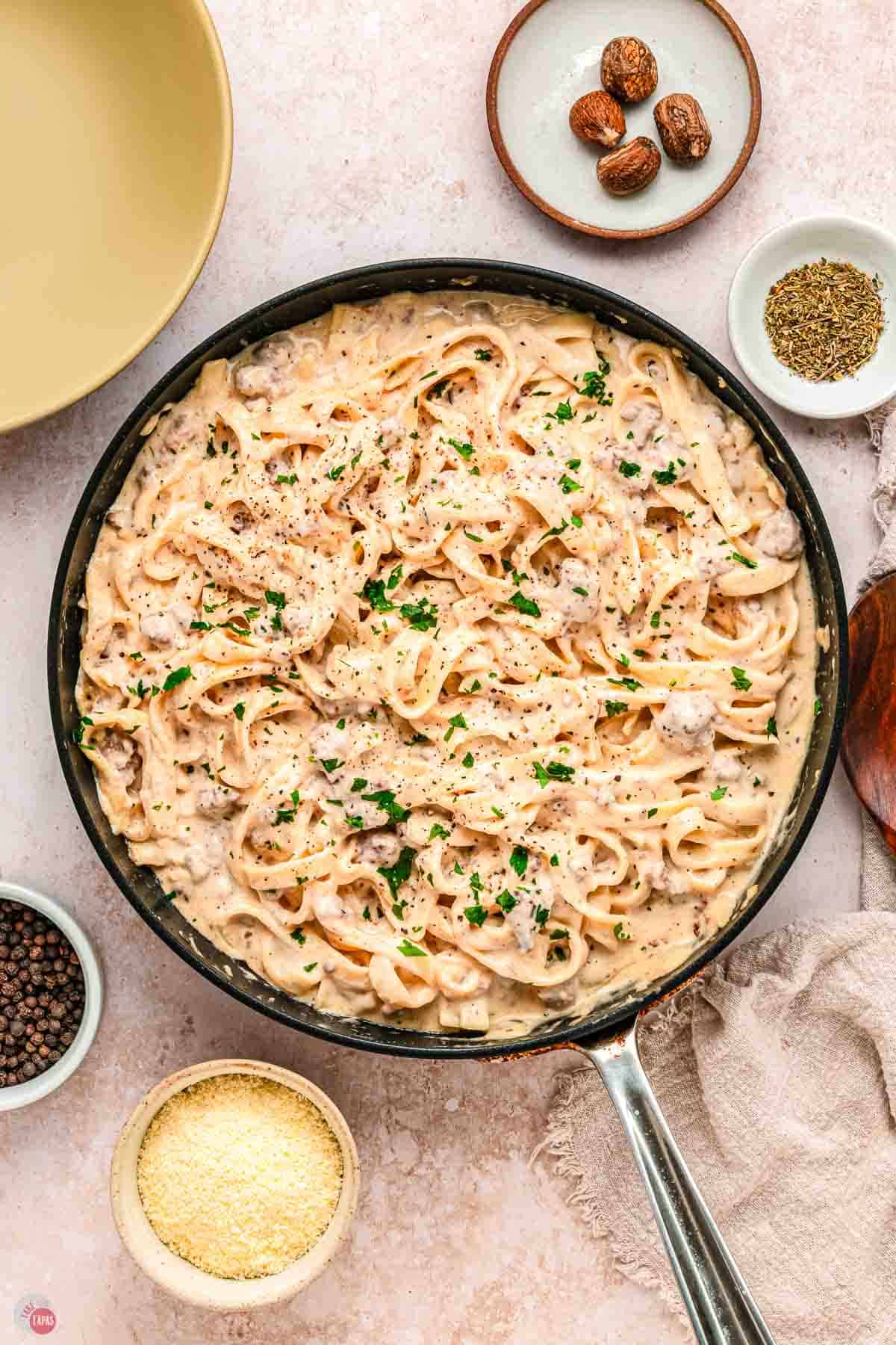 overhead picture of skillet with pasta surrounded by small bowls of garnishes