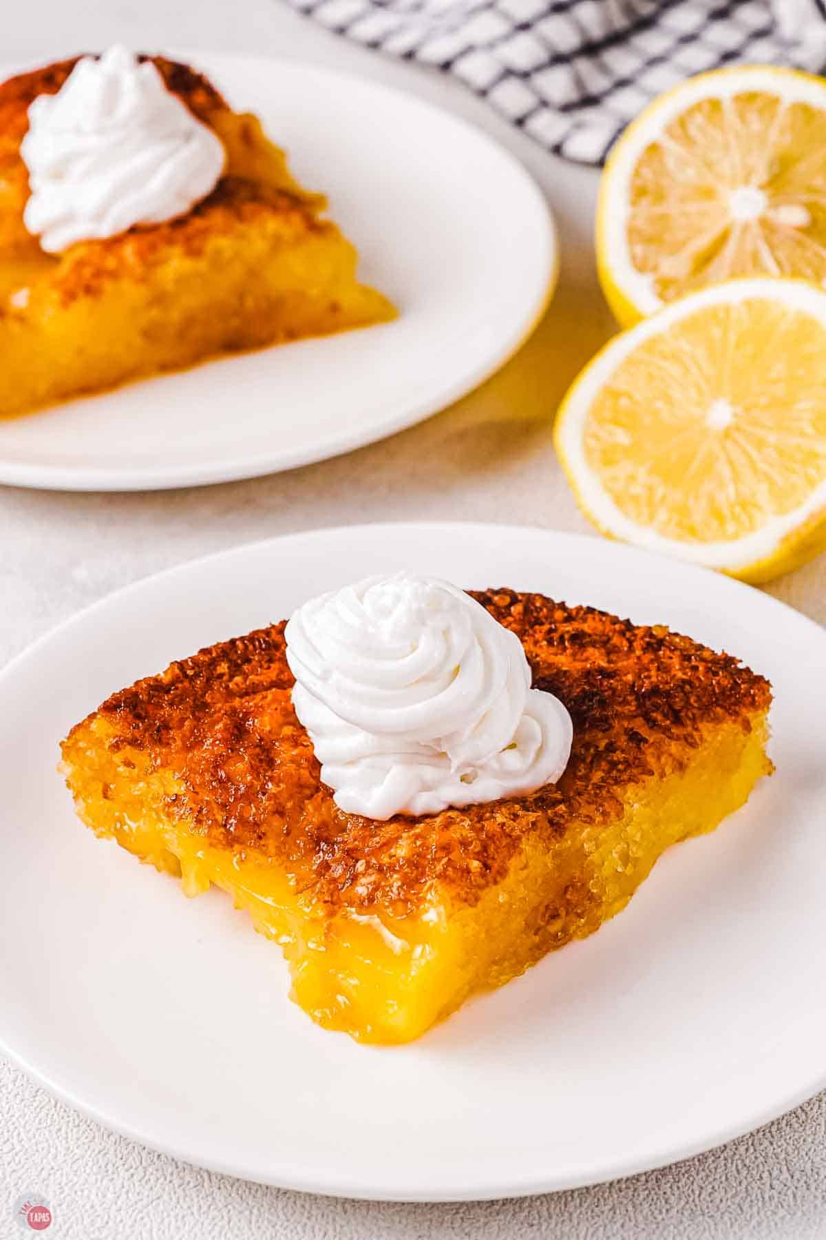 slice of cobbler on a white plate with whipped cream on top and sliced lemons next to it