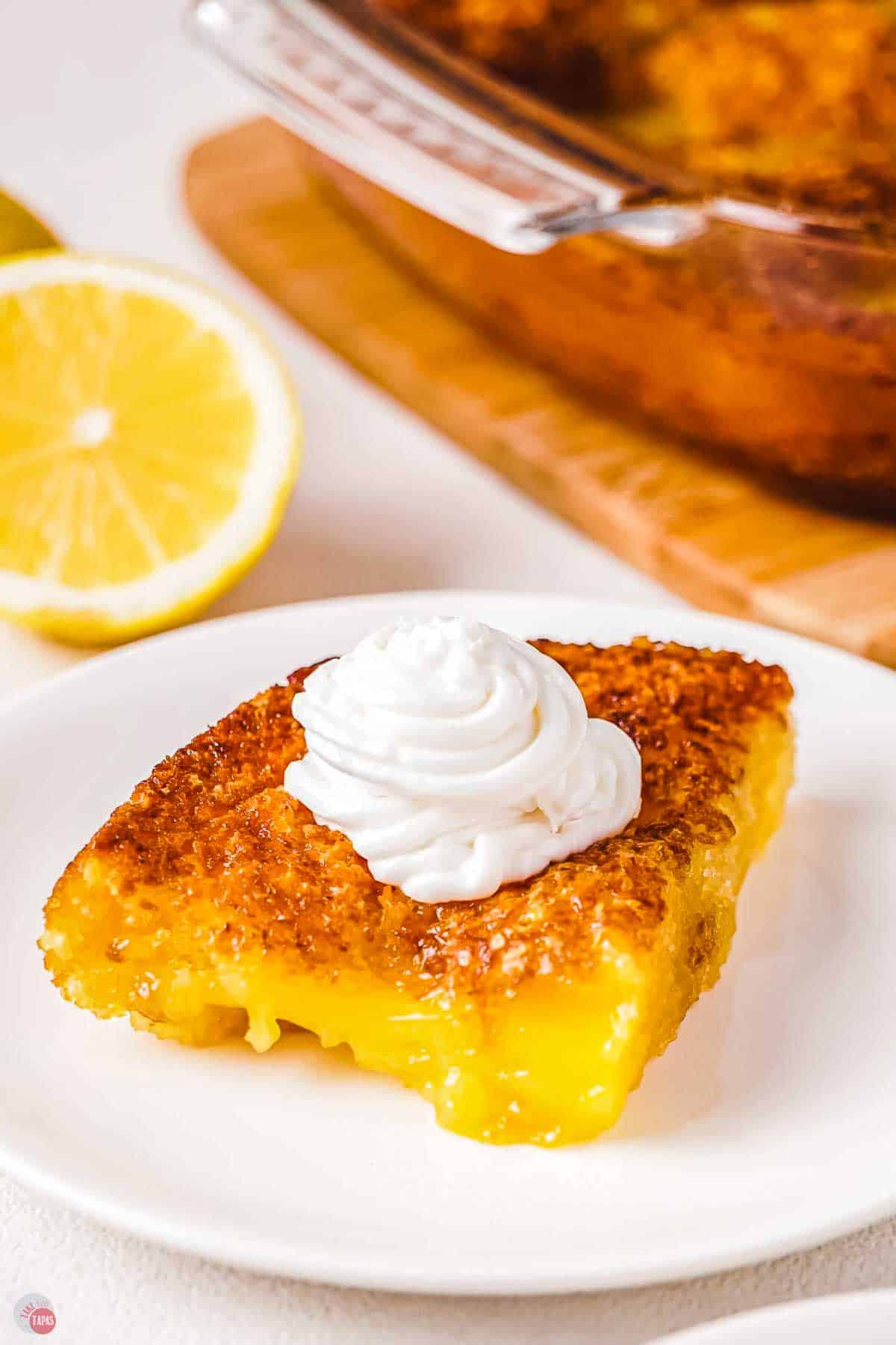 slice of lemon cobbler on a white plate topped with whipped cream