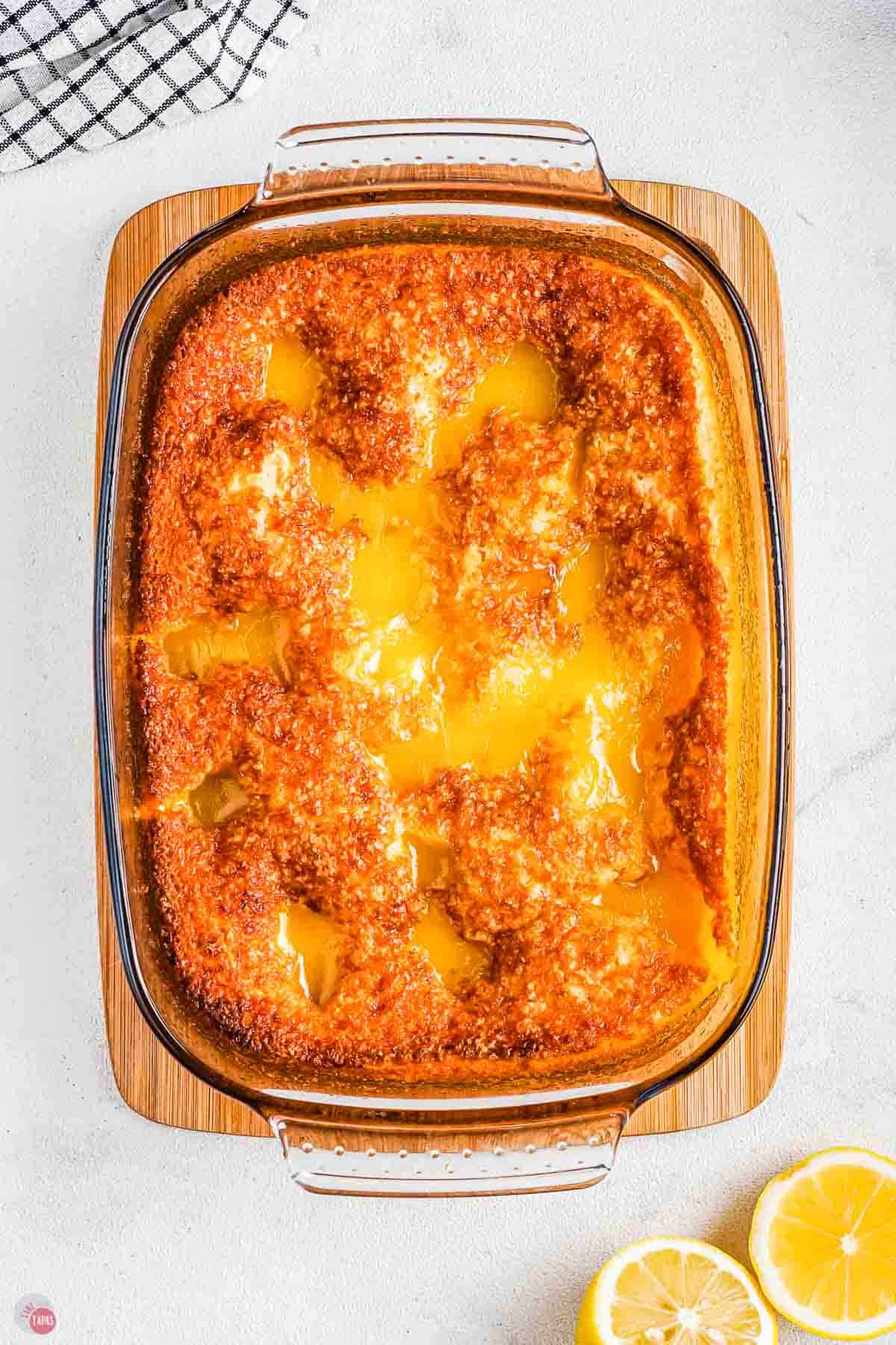baked lemon dessert in a clear 9x13 dish on a wood board