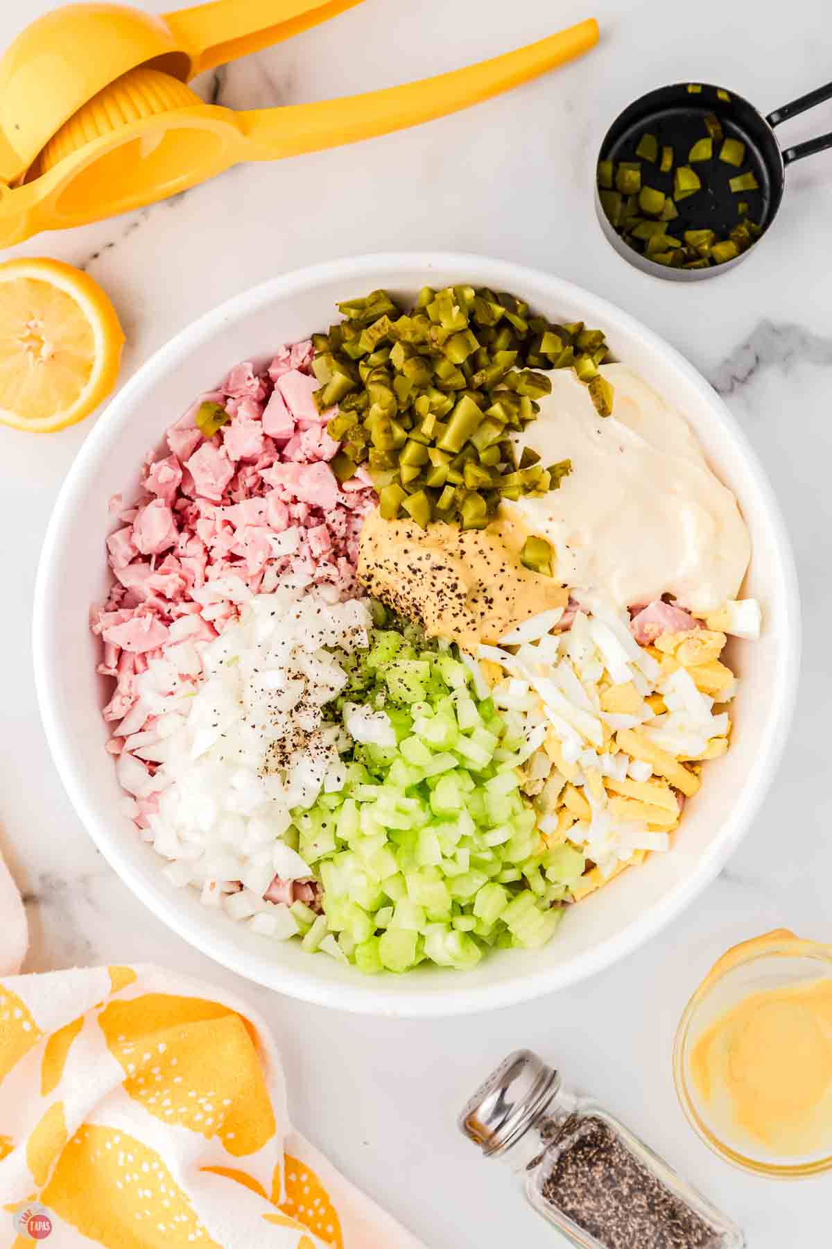 white bowl with diced ham, celery, pickles, onion, and dressing in it but unmixed