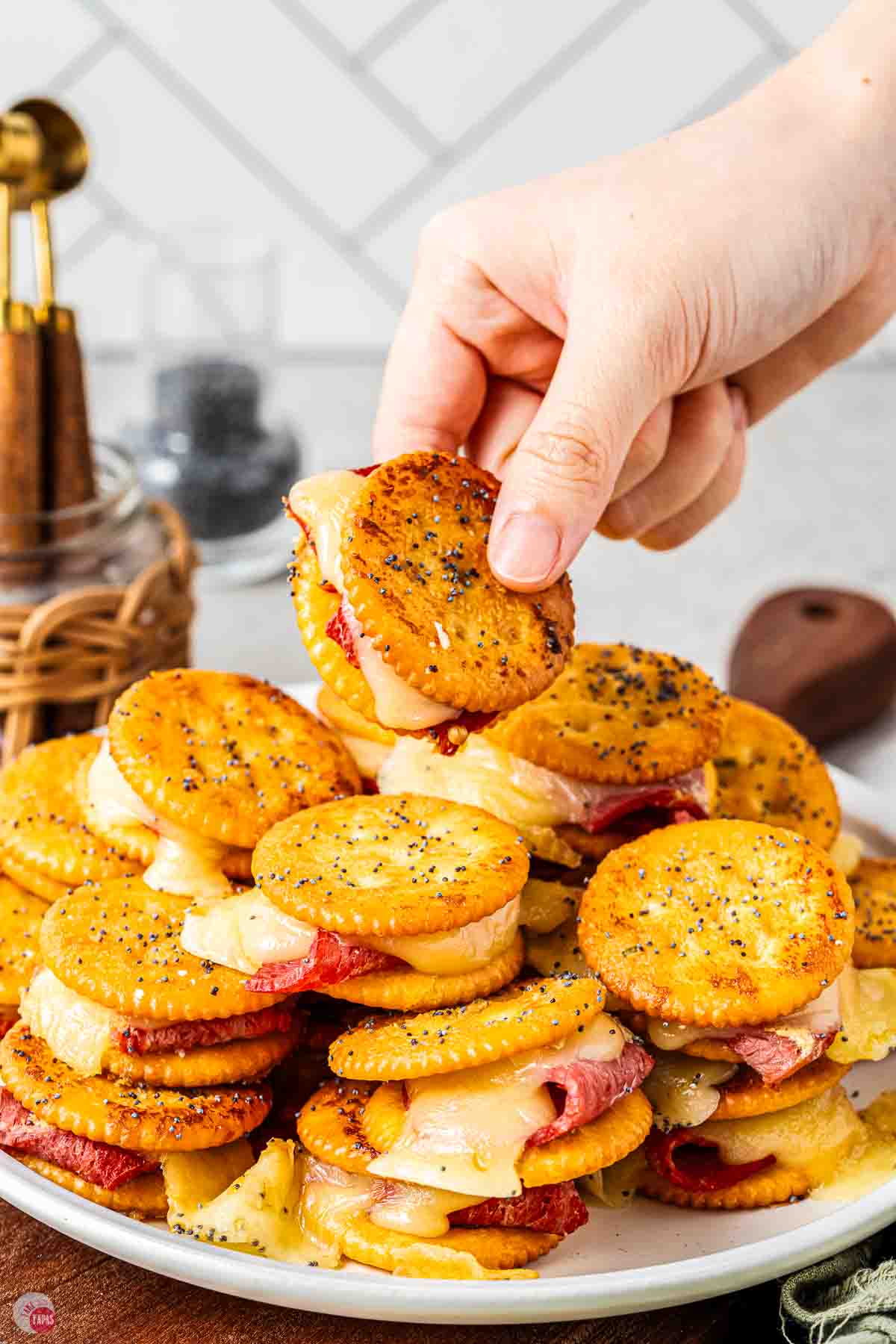 plate of cracker sandwiches with a hand grabbing one off the top