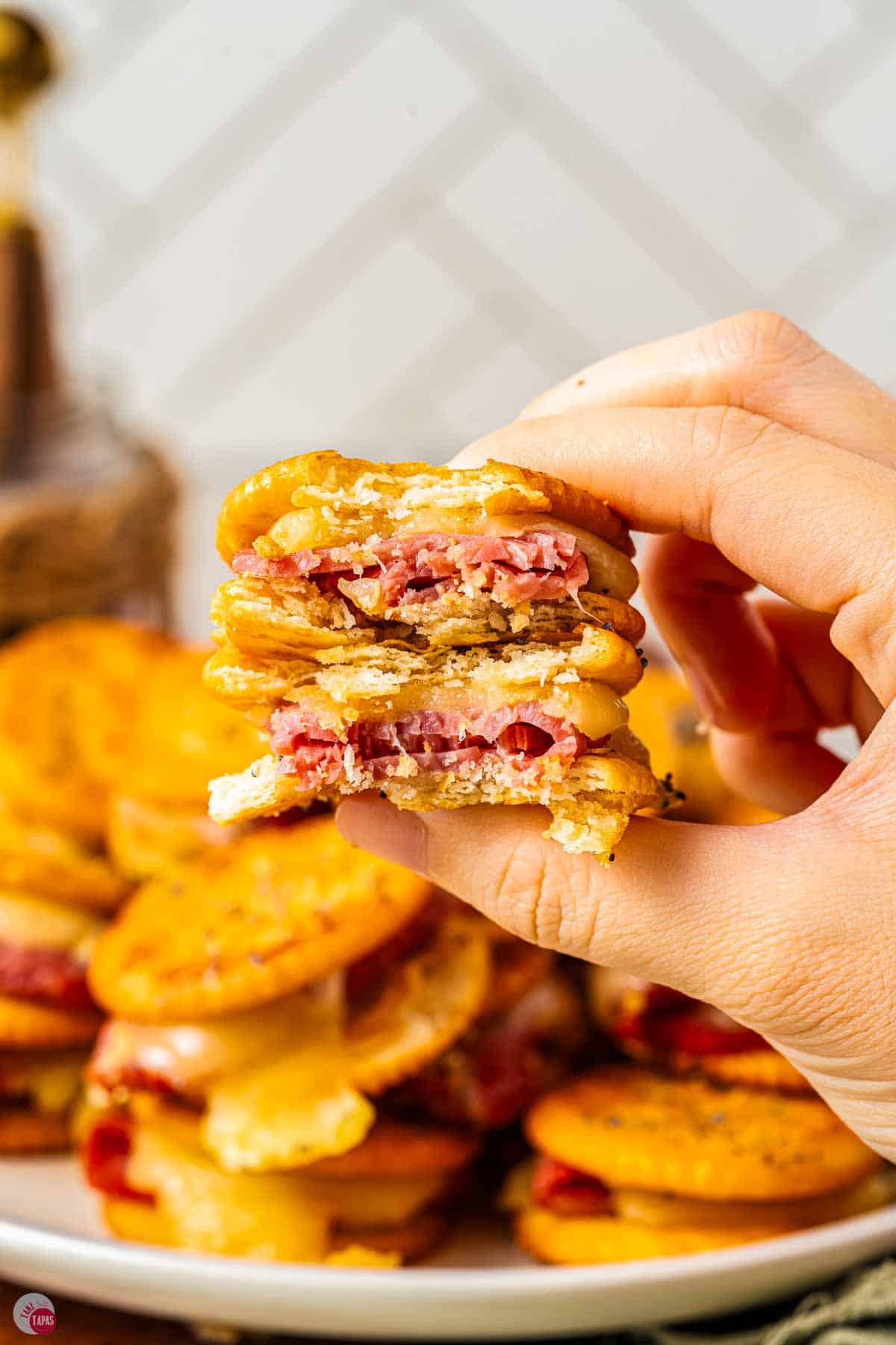 hand holding two crackers with a bite missing