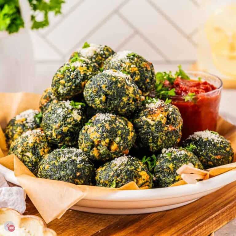 spinach balls in a white bowl with parchment paper