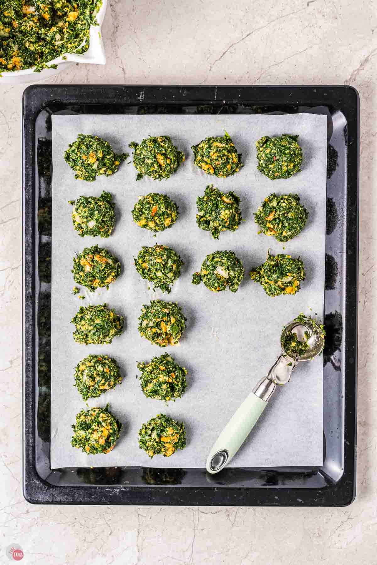 spinach balls on a baking sheet lined with parchment paper