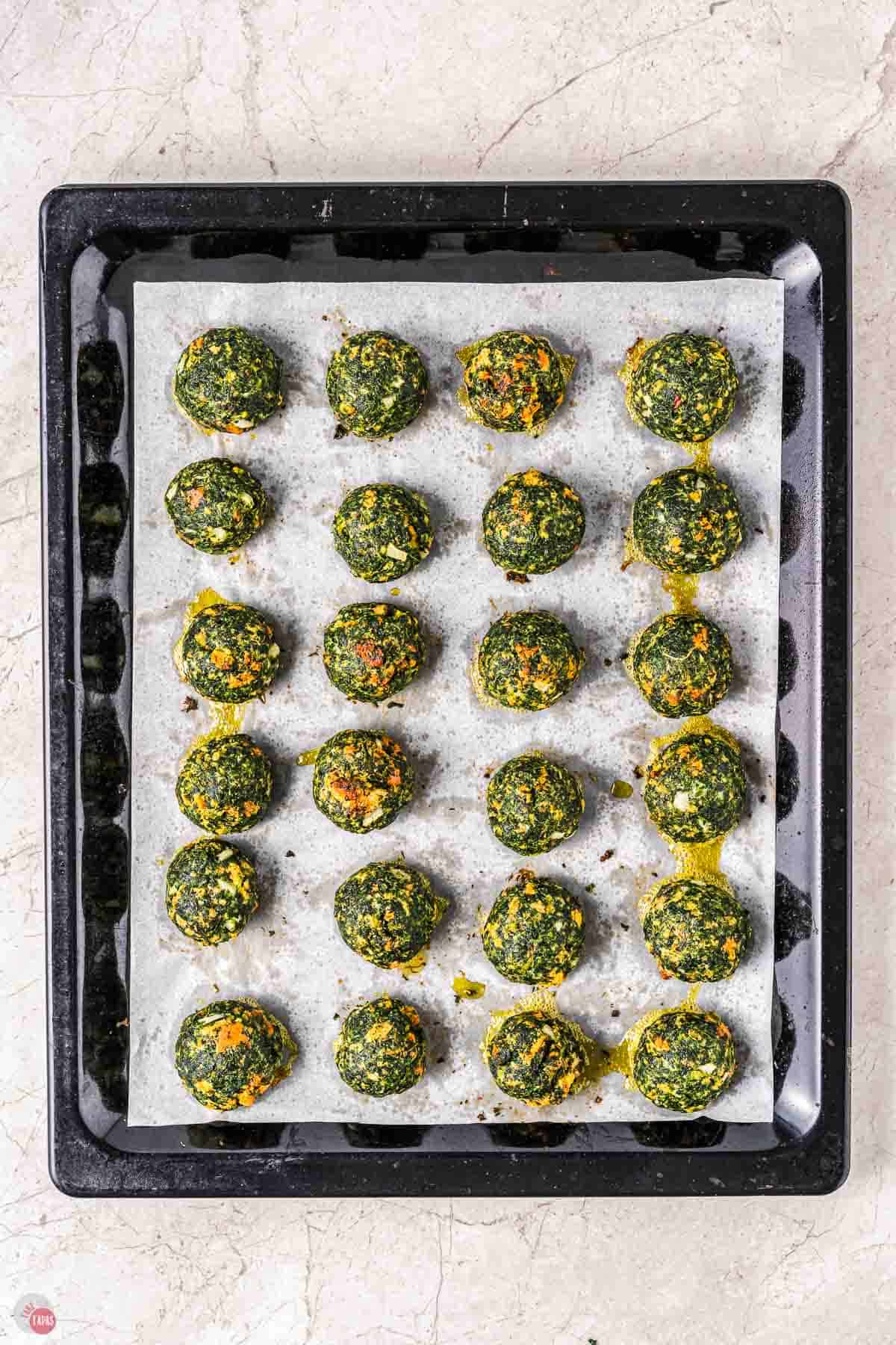 baked spinach balls on a baking sheet with parchment paper