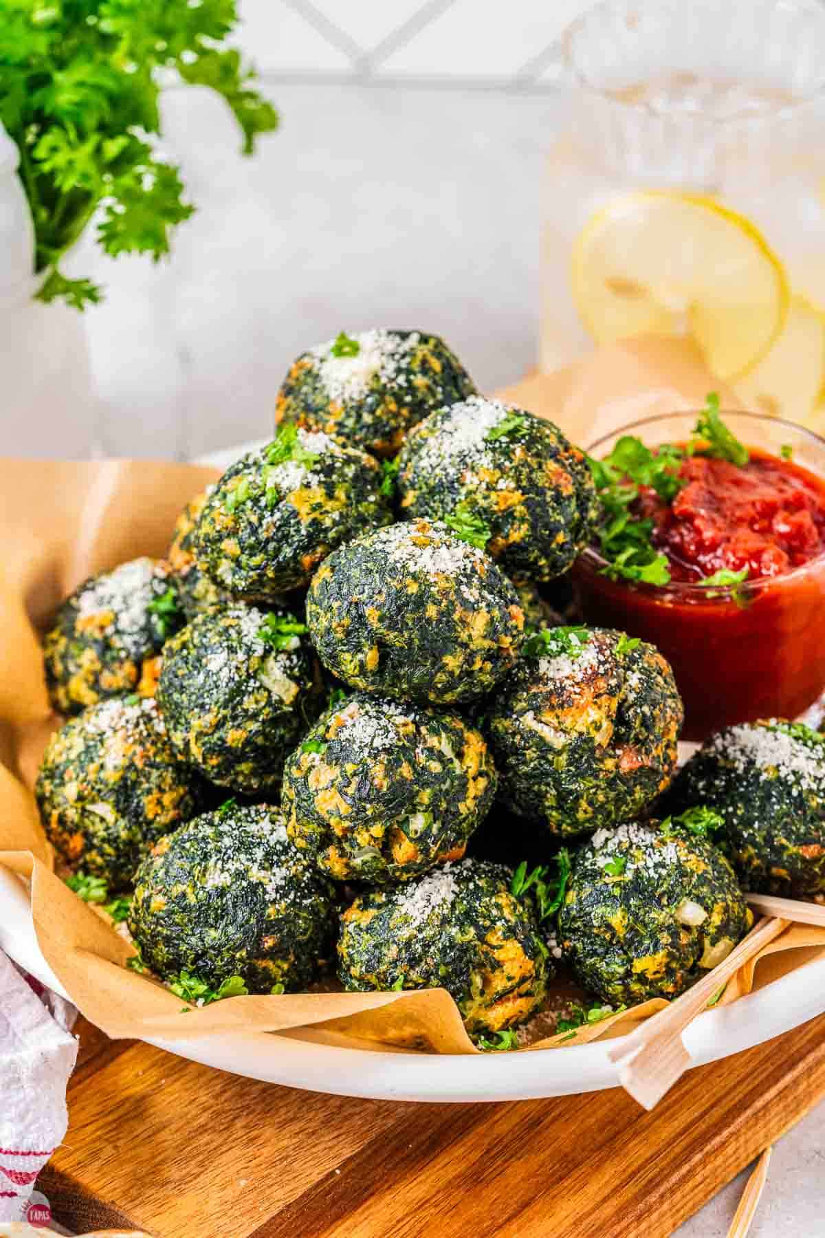 plate of baked spinach balls with marinara sauce in a small jar