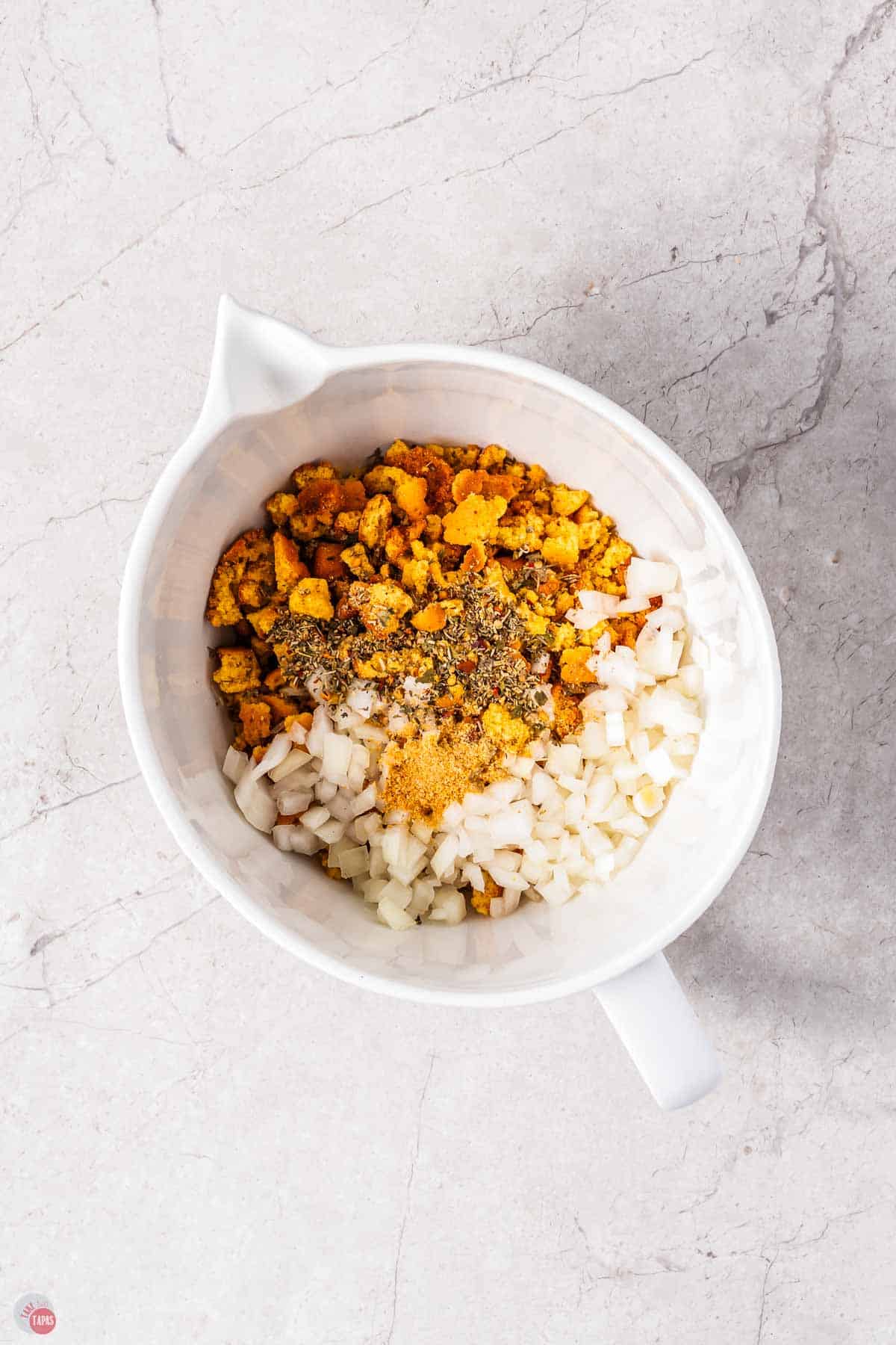 white mixing bowl with dressing, onion, and spices in it