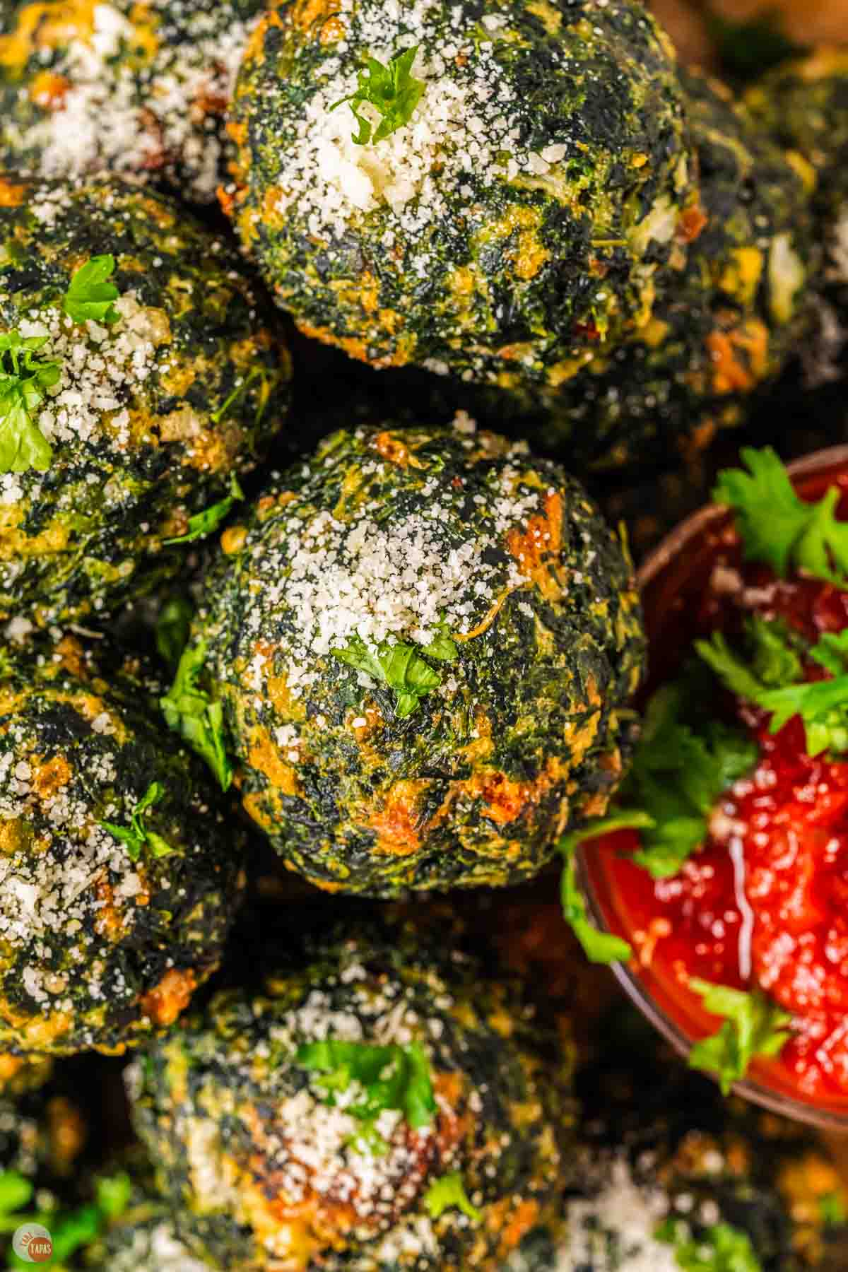 close up of spinach balls sprinkled with grated cheese