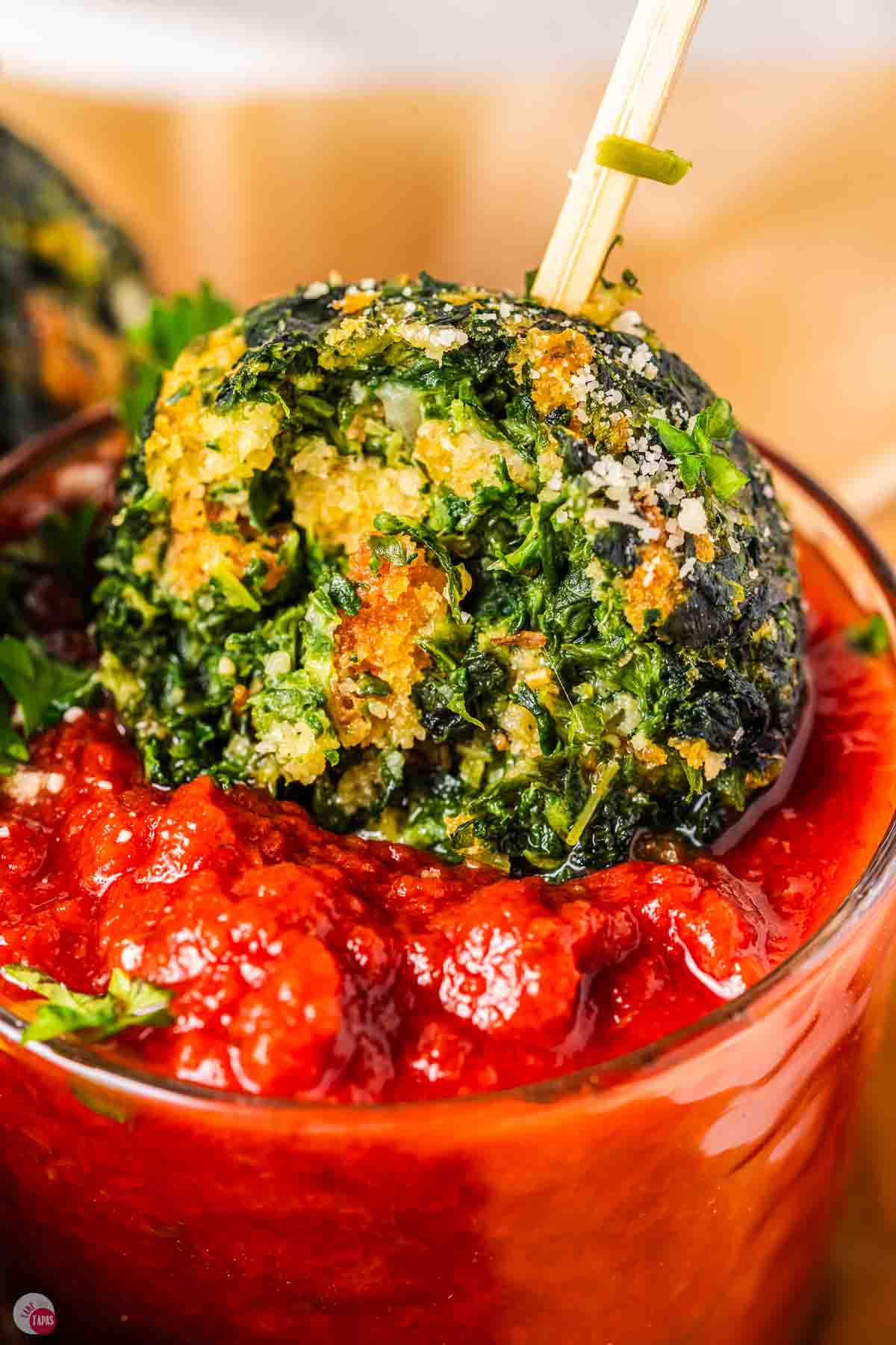 close up of spinach ball in a small jar of tomato sauce