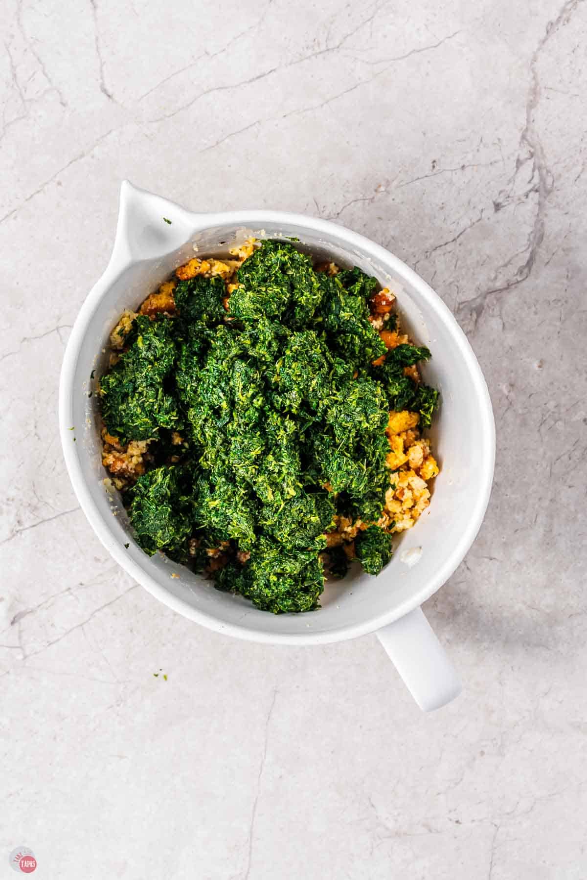 white mixing bowl with chopped frozen spinach on top