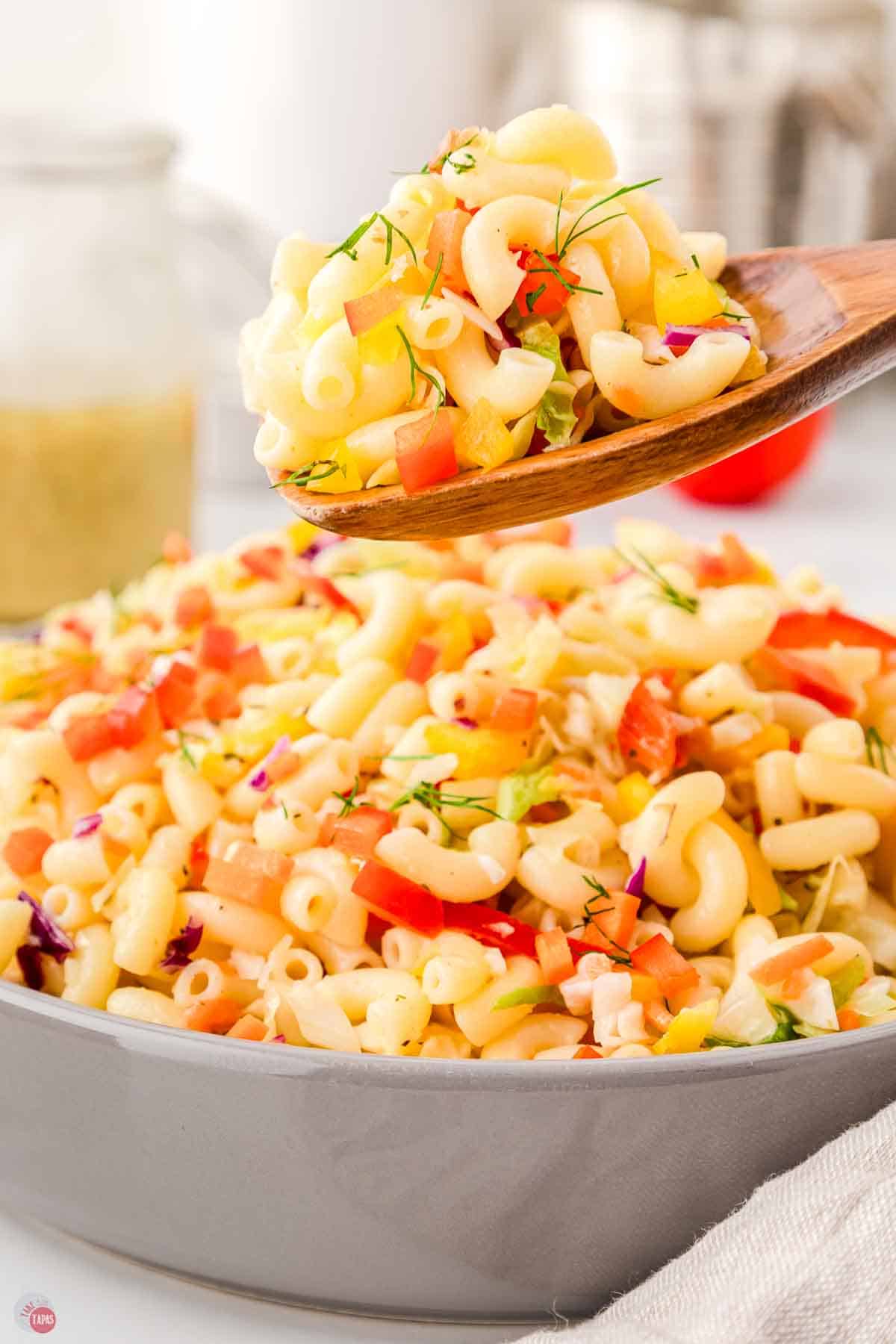 bowl of pasta and a wood spoon scooping some out