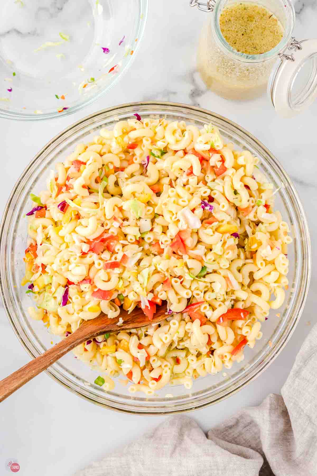 mixing bowl with pasta salad and a wood spoon in it