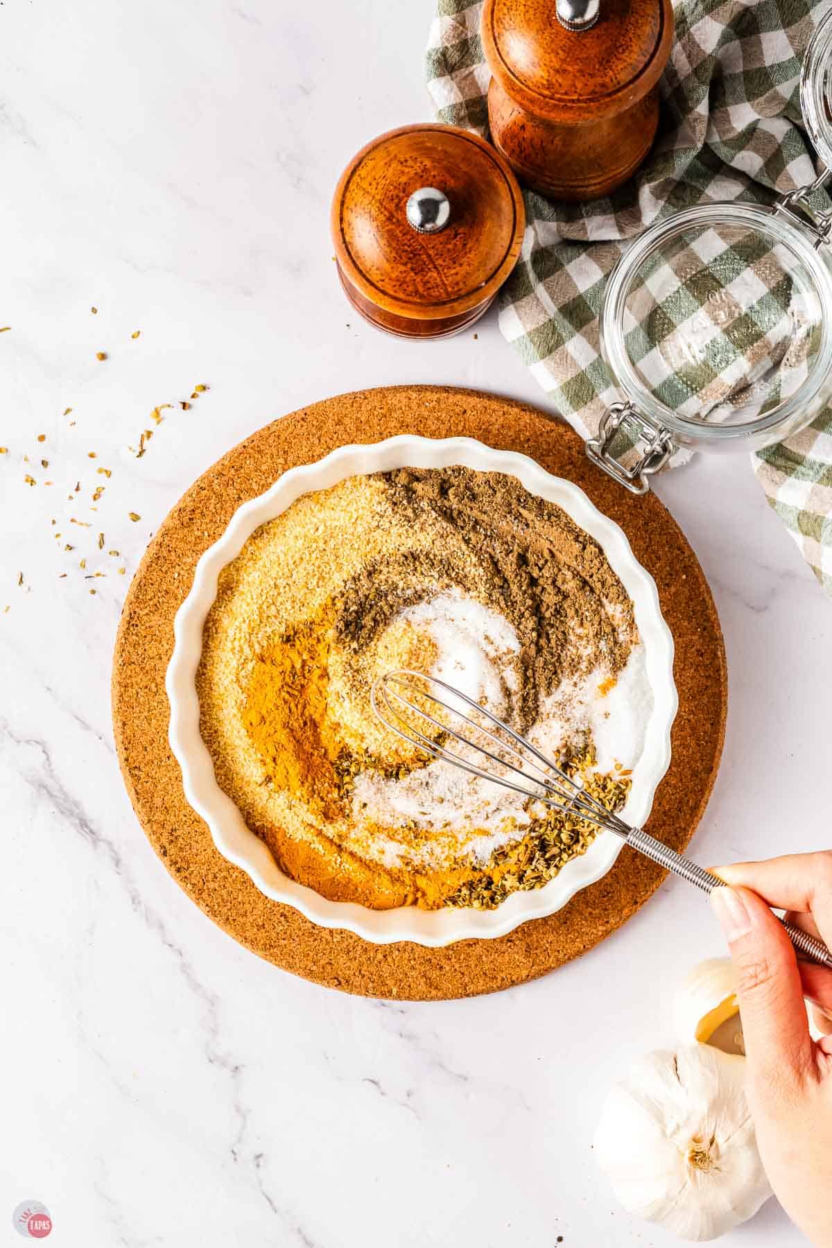 hand mixing spices in a shallow bowl