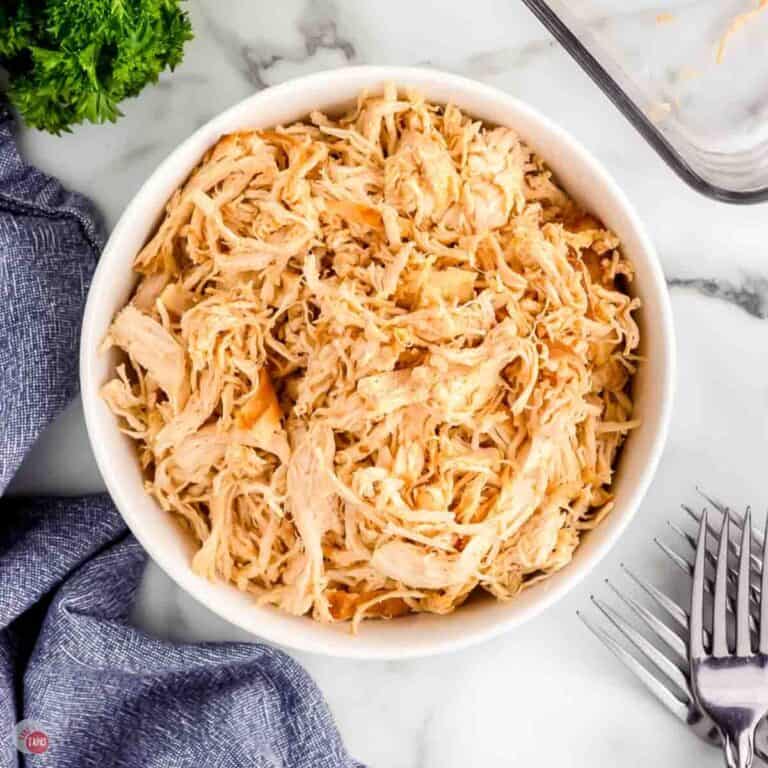 white bowl with shredded chicken and two forks