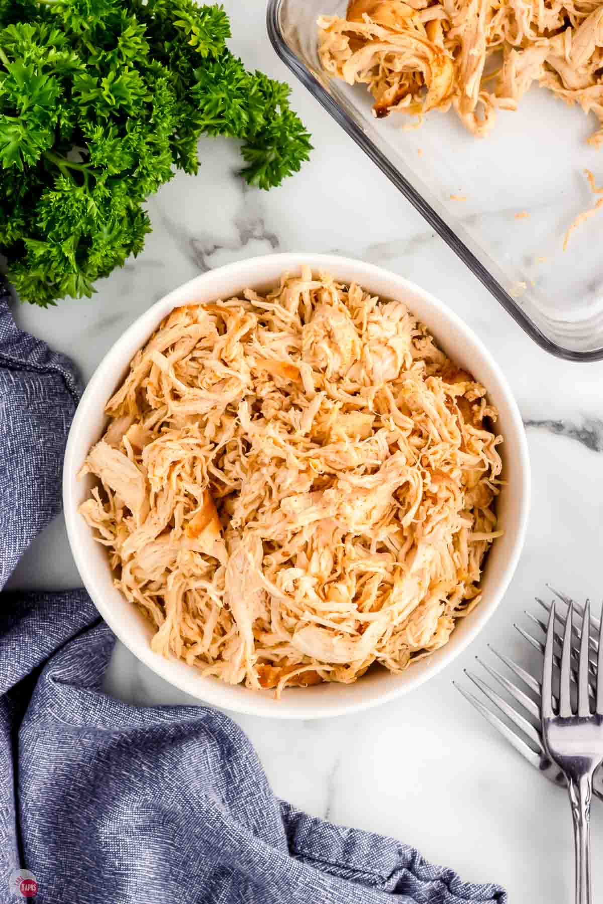 bowl of shredded chicken next to two forks