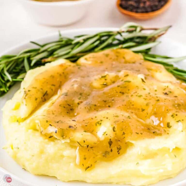 plate of mashed potatoes topped with gravy and a sprig of rosemary