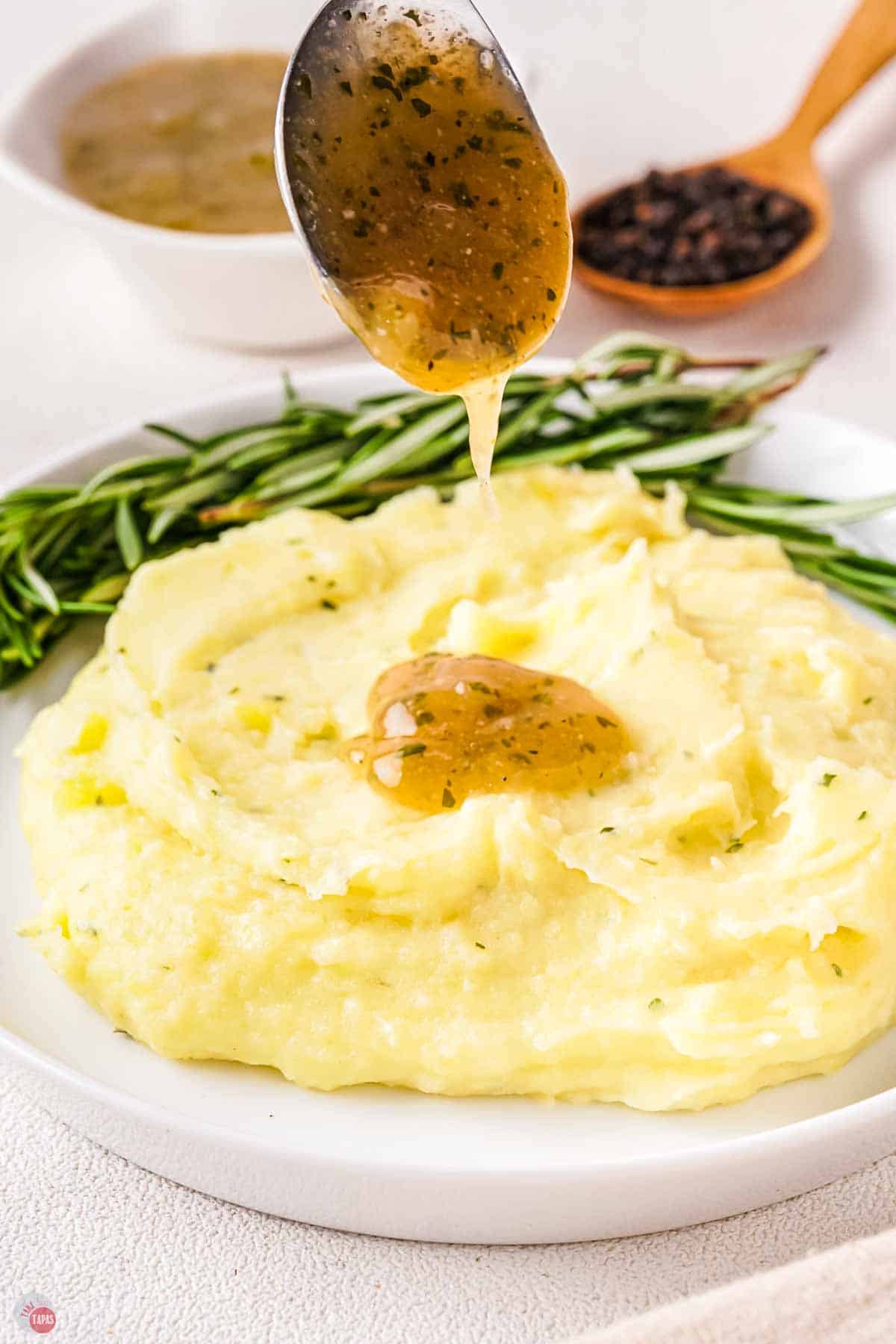 pile of mashed potatoes with a spoon drizzling au jus on top of it