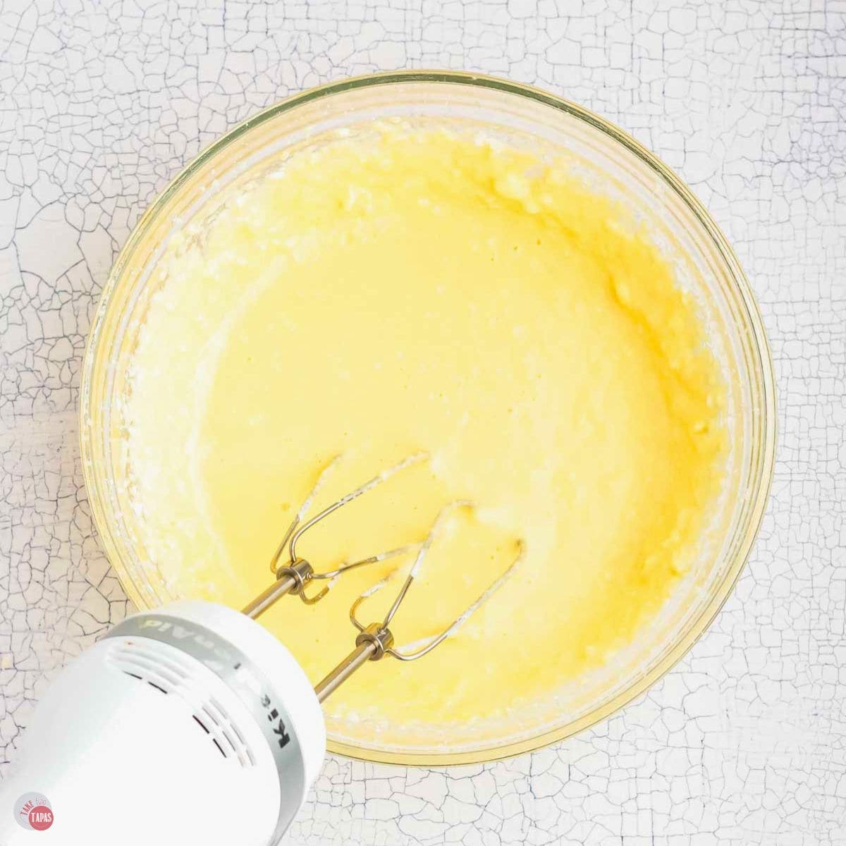 coffee cake batter being mixed in a clear bowl with a hand mixer
