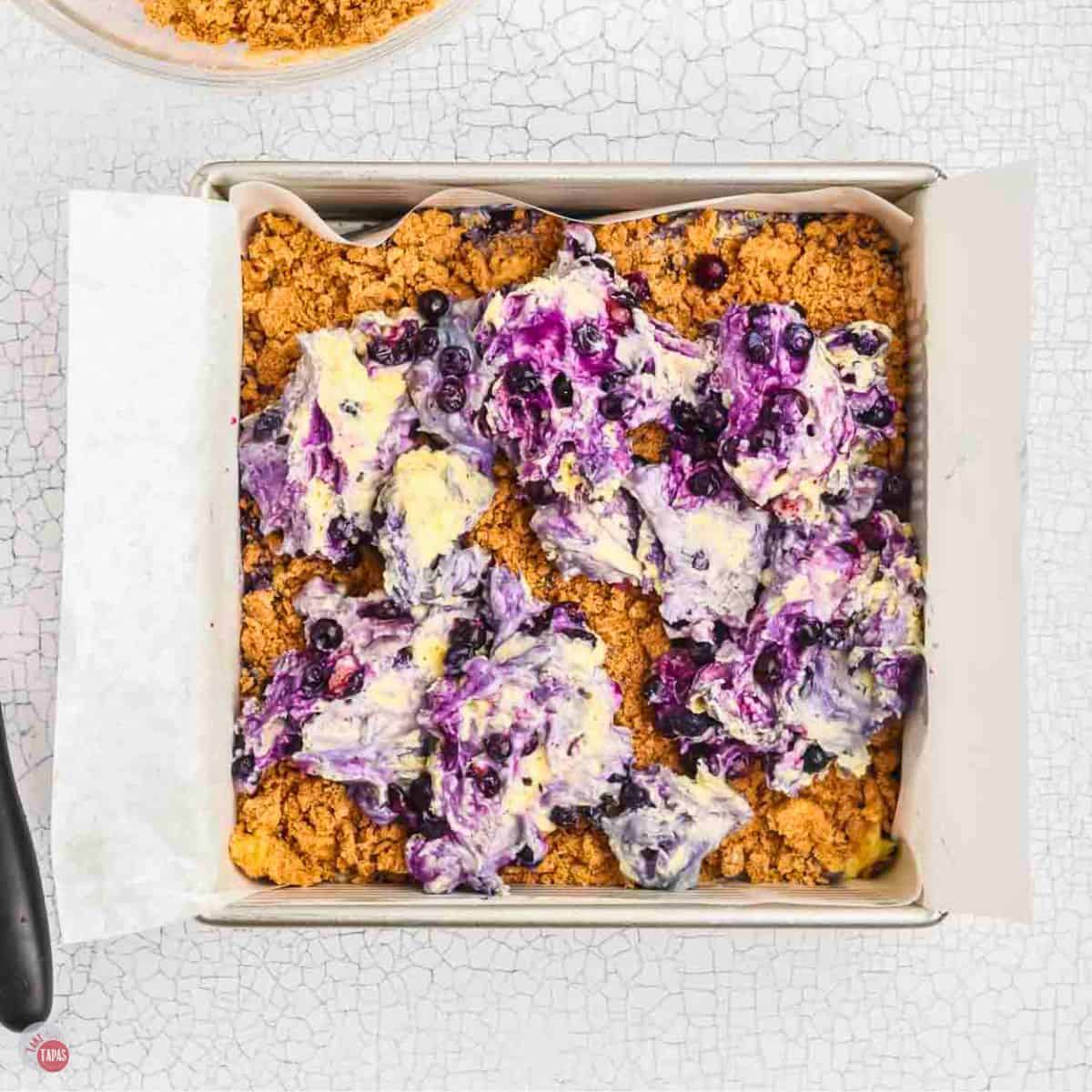 square baking pan with crust and batter spooned into it