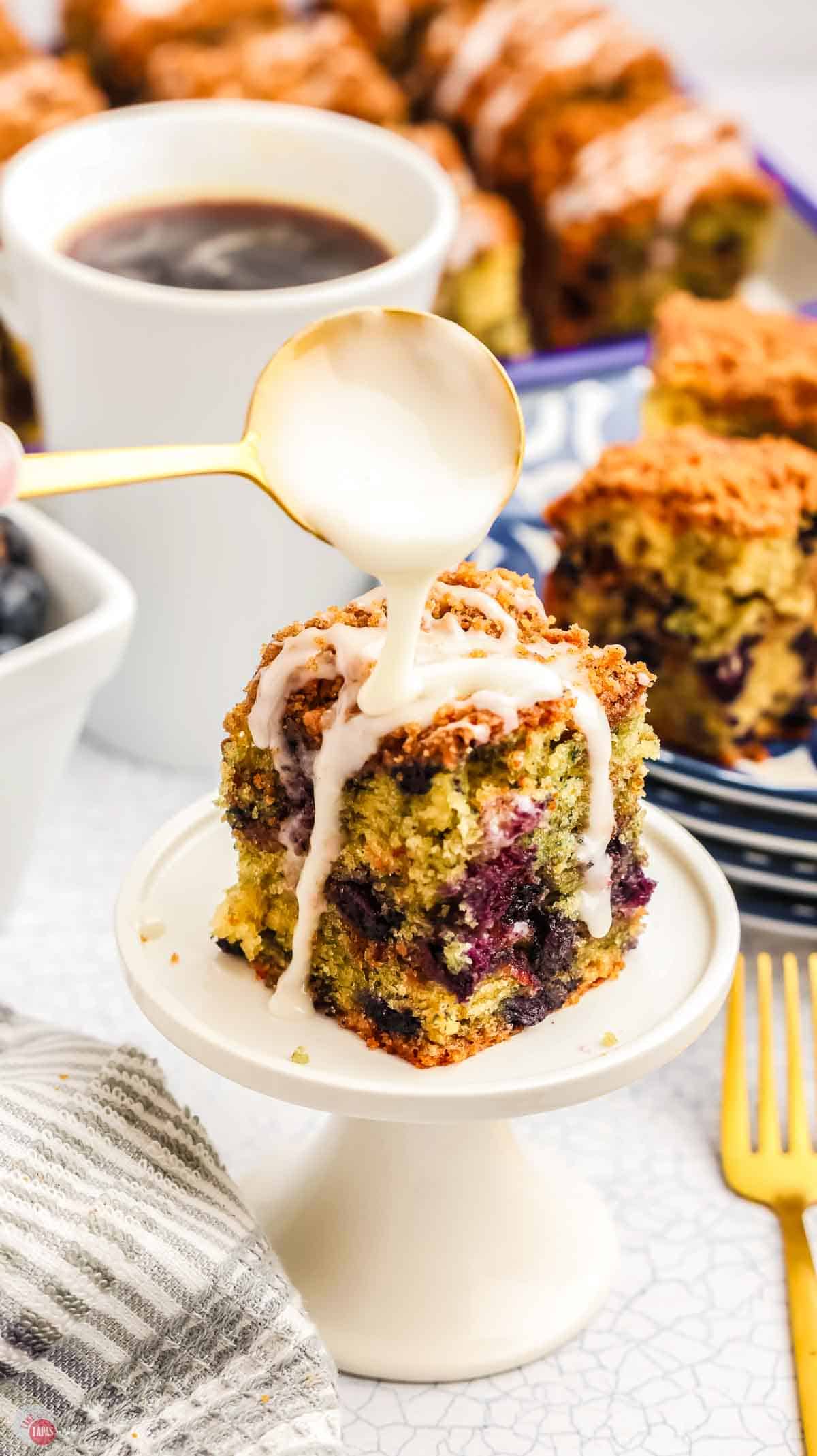 slice of cake being drizzled with lemon glaze