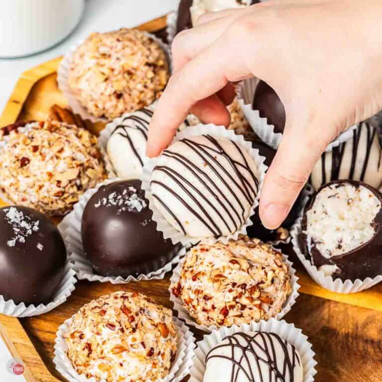hand grabbing a bourbon ball drizzled with chocolate from a stack of them