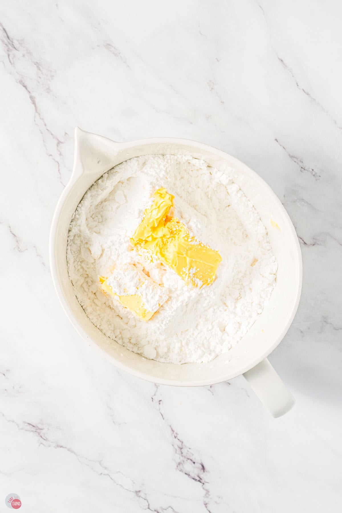 powdered sugar and butter in a white mixing bowl