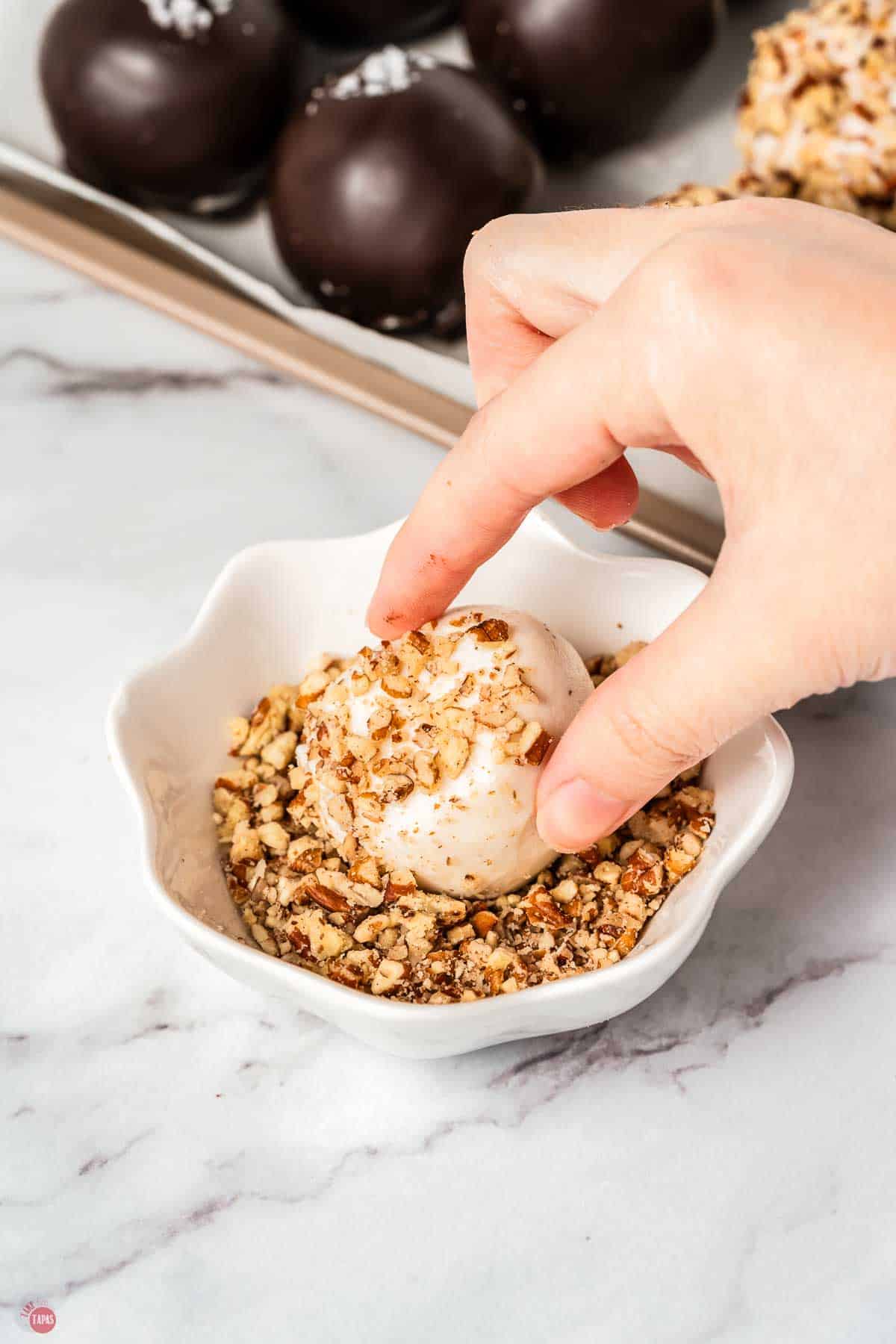 hand dipping ball in chopped pecans