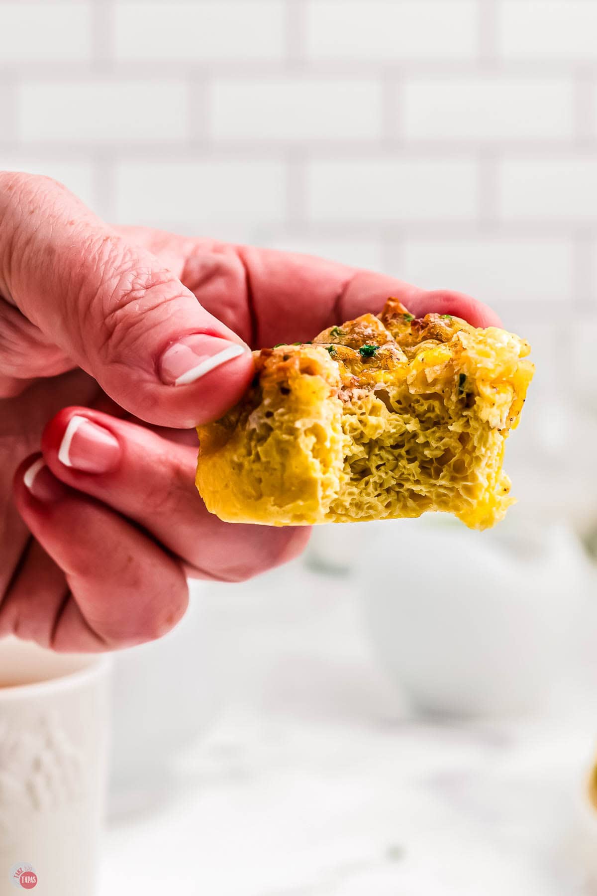 hand holding an egg muffin with a bite taken out of it