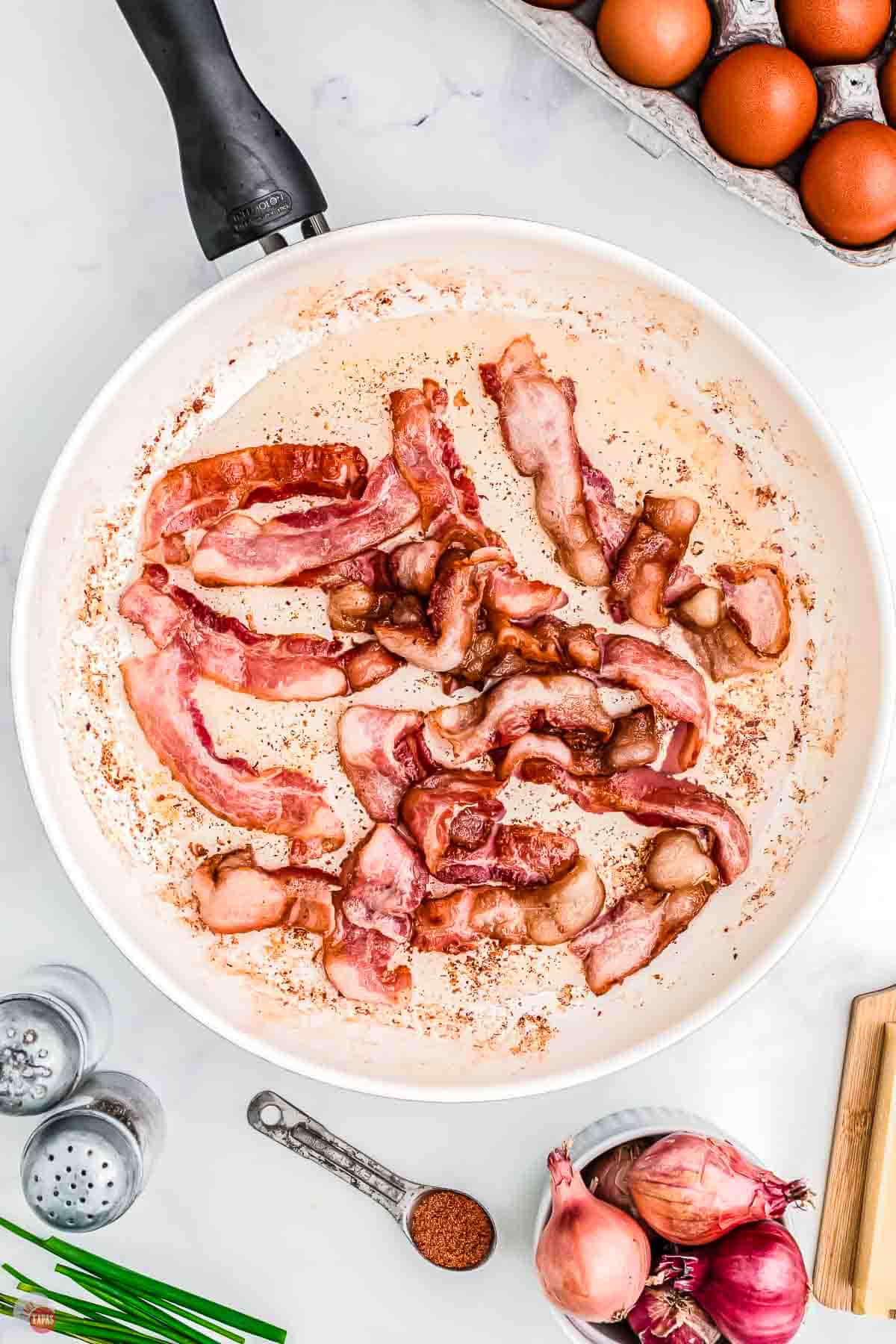 strips of bacon cooking in a skillet