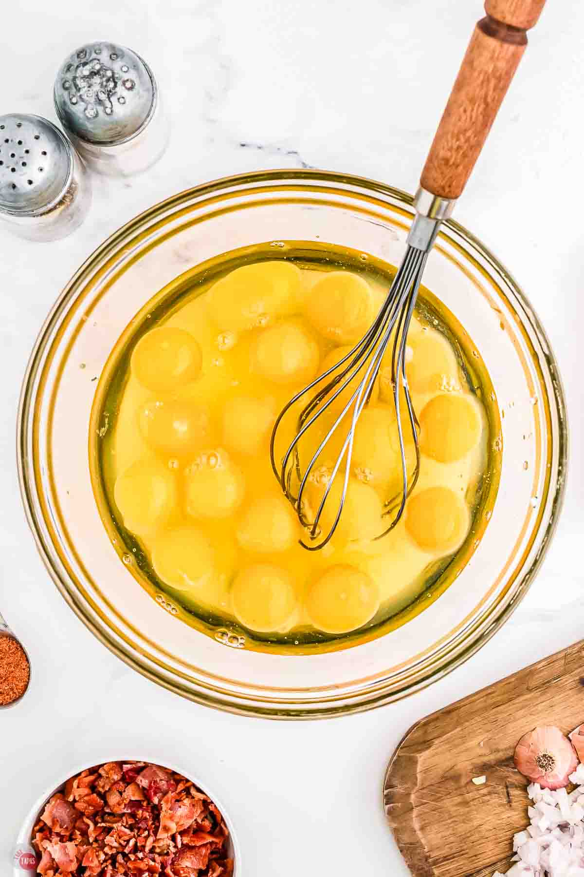 clear bowl full of eggs with a whisk