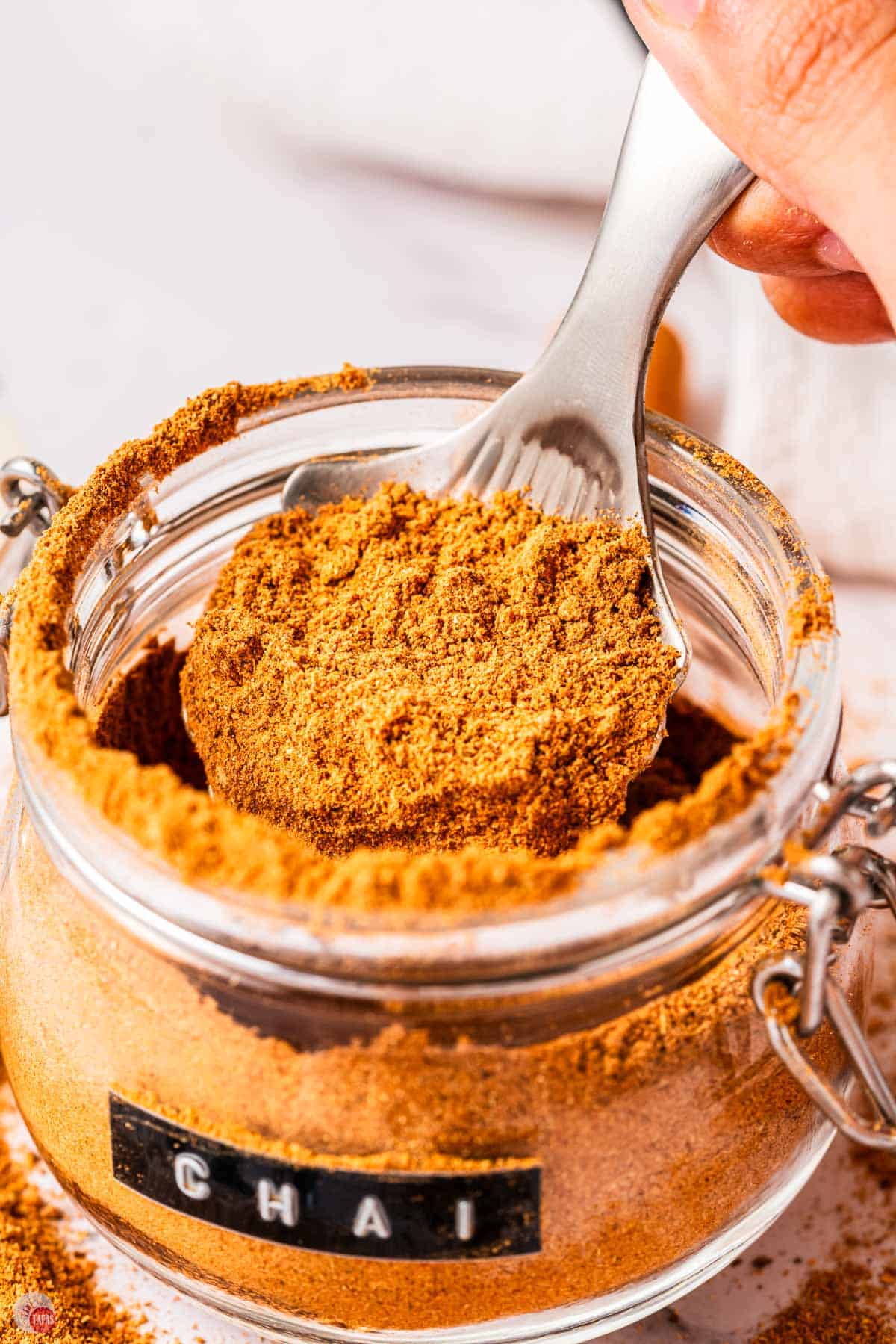close up of spices in a jar with a silver spoon