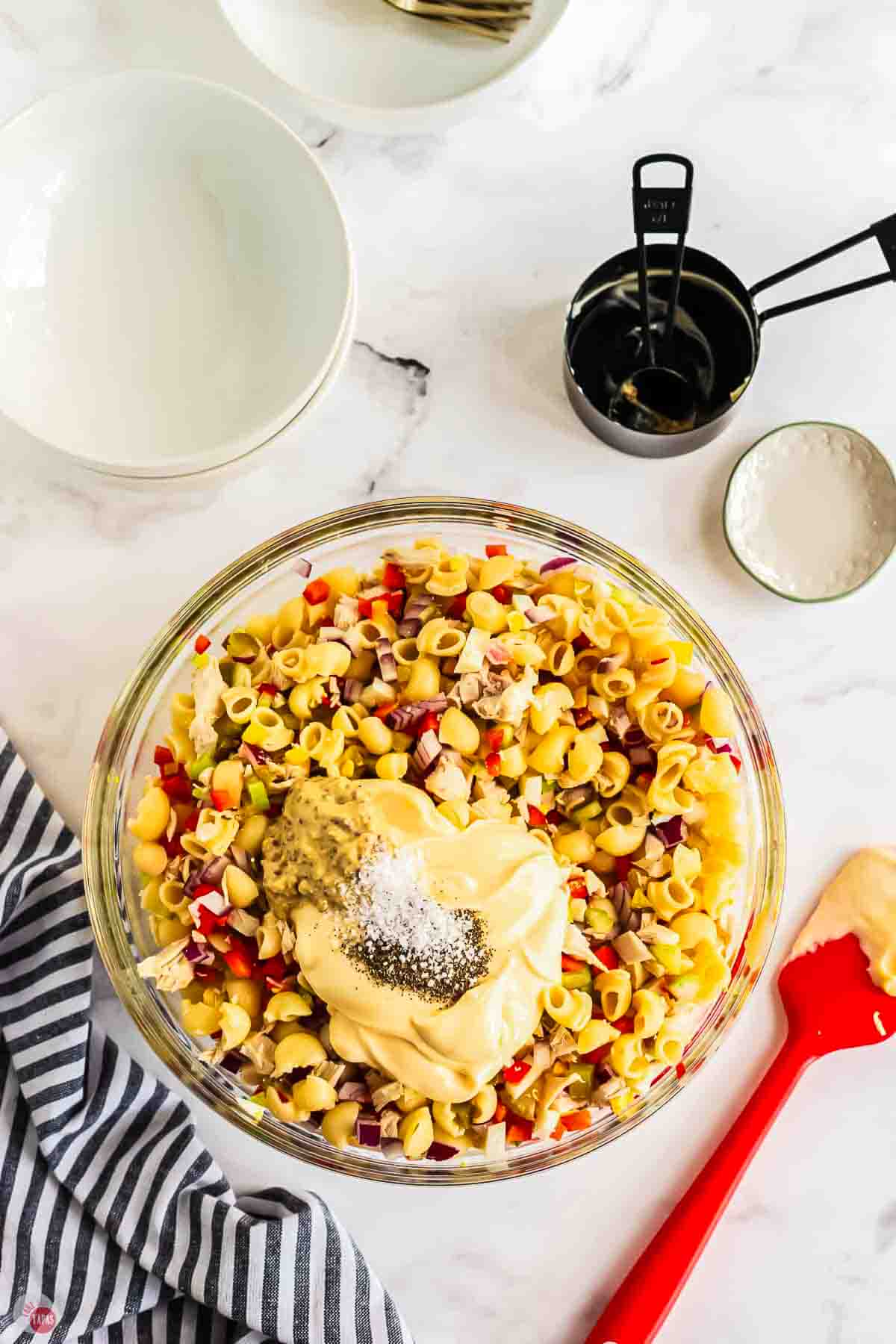 undressed pasta salad in a clear mixing bowl