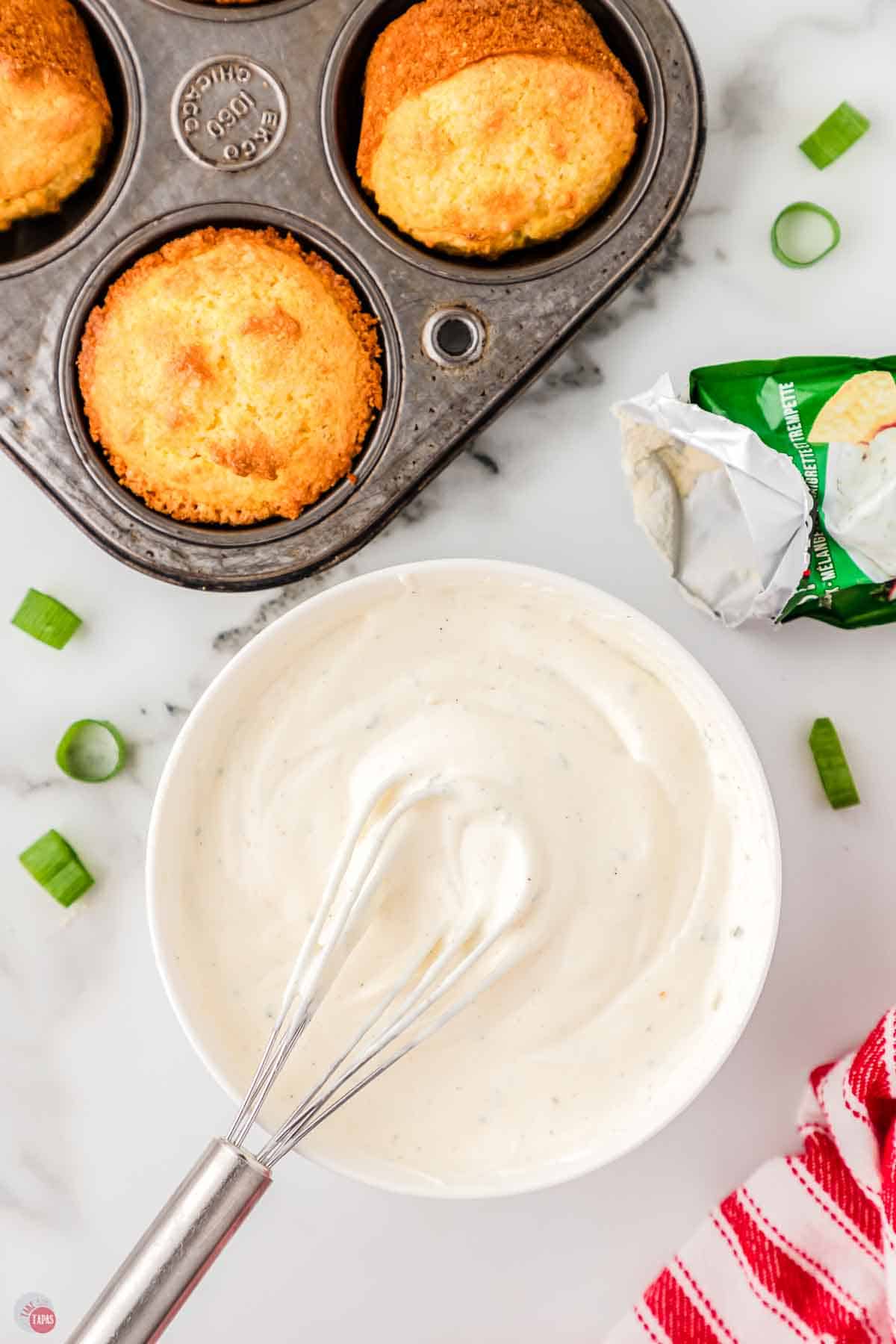 small white bowl with a creamy dressing and a whisk