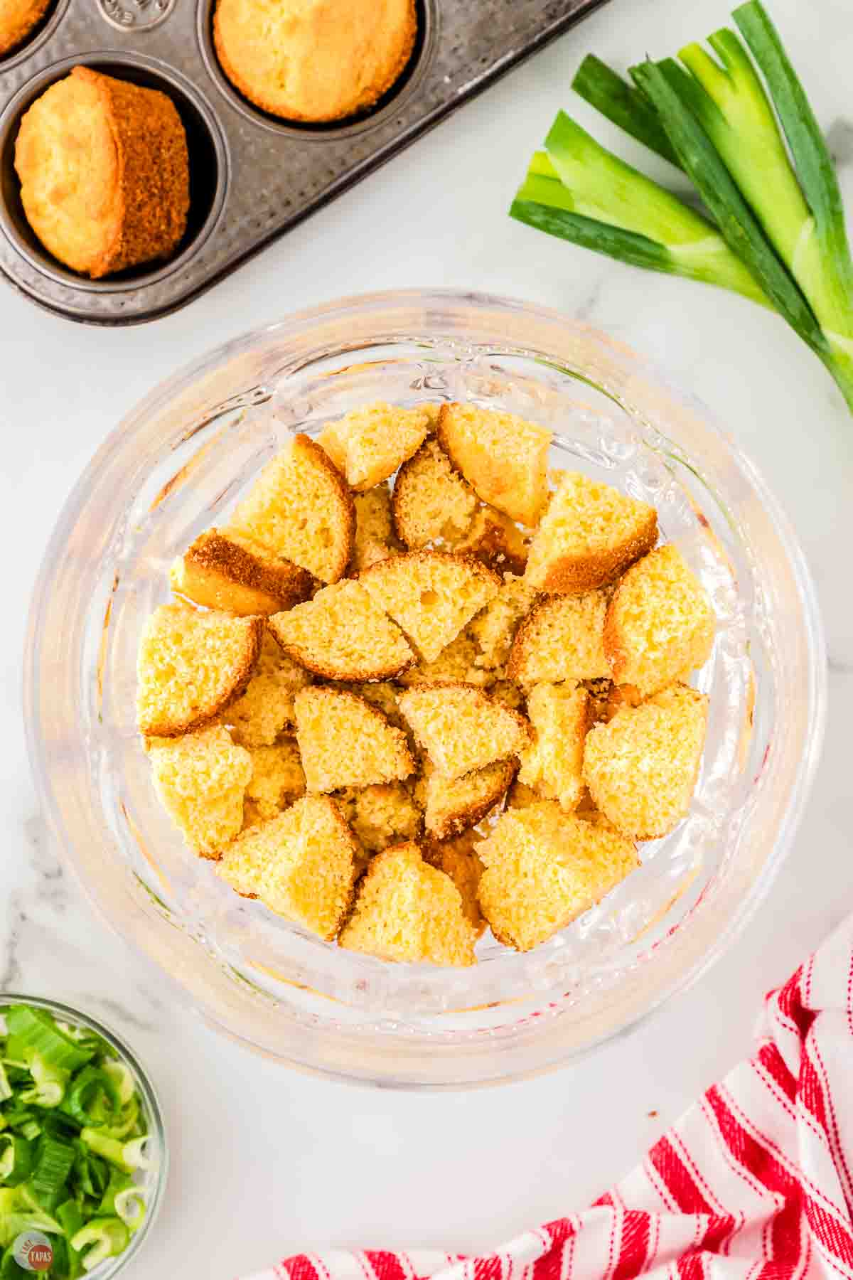 a clear trifle bowl with chunks of cornbread in the bottom