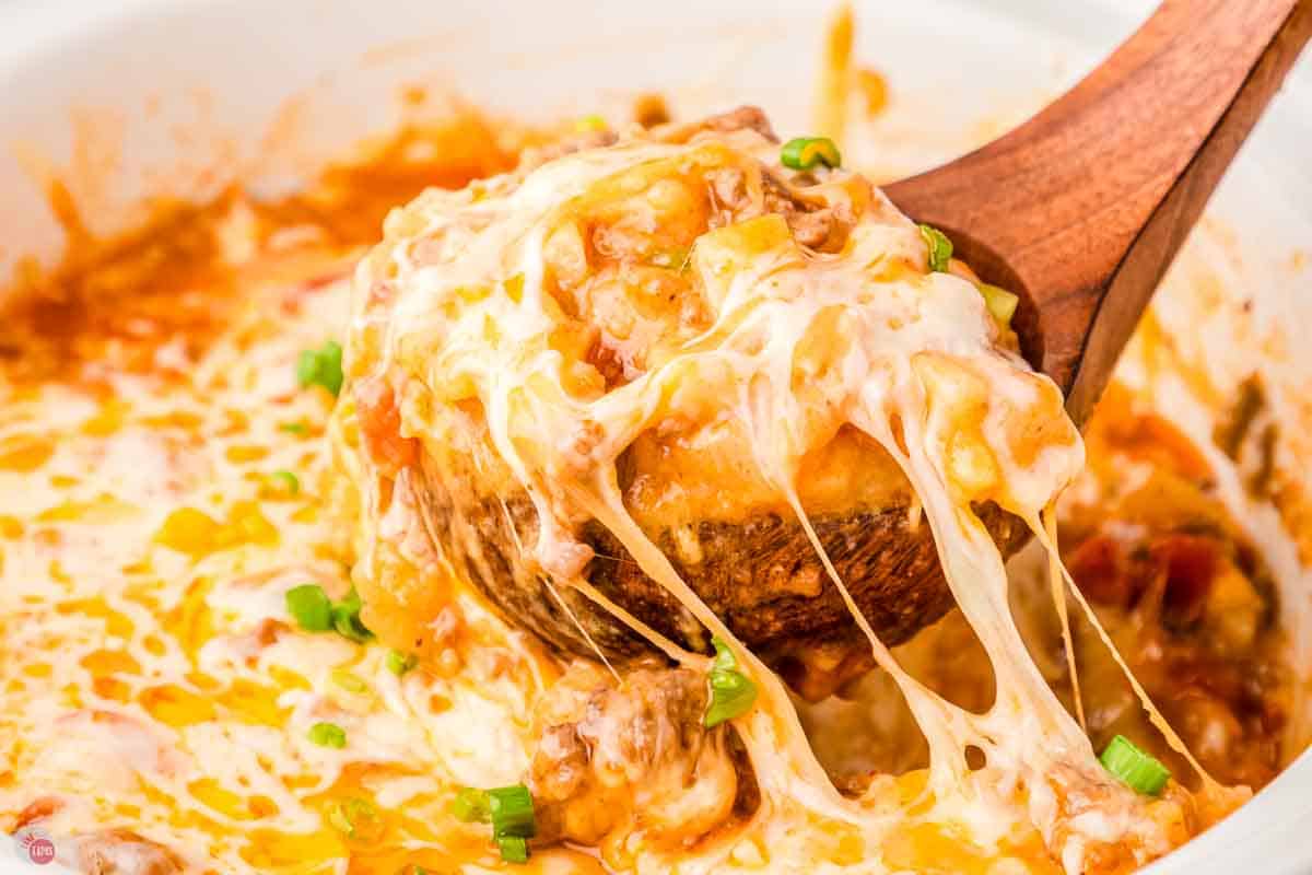 close up of wood spoon scooping a cheese recipe out of a white bowl