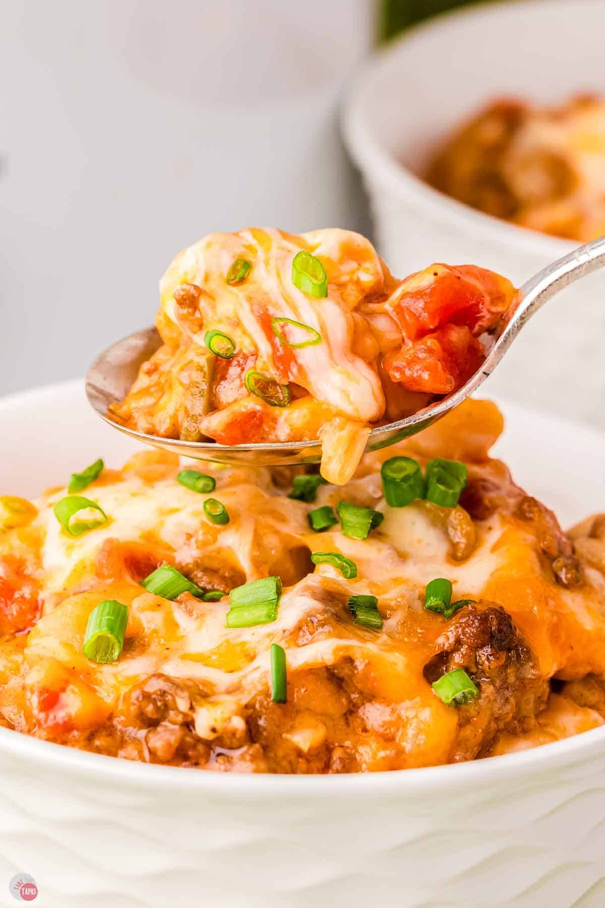 spoon with bite of Mexican casserole on it over a bowl