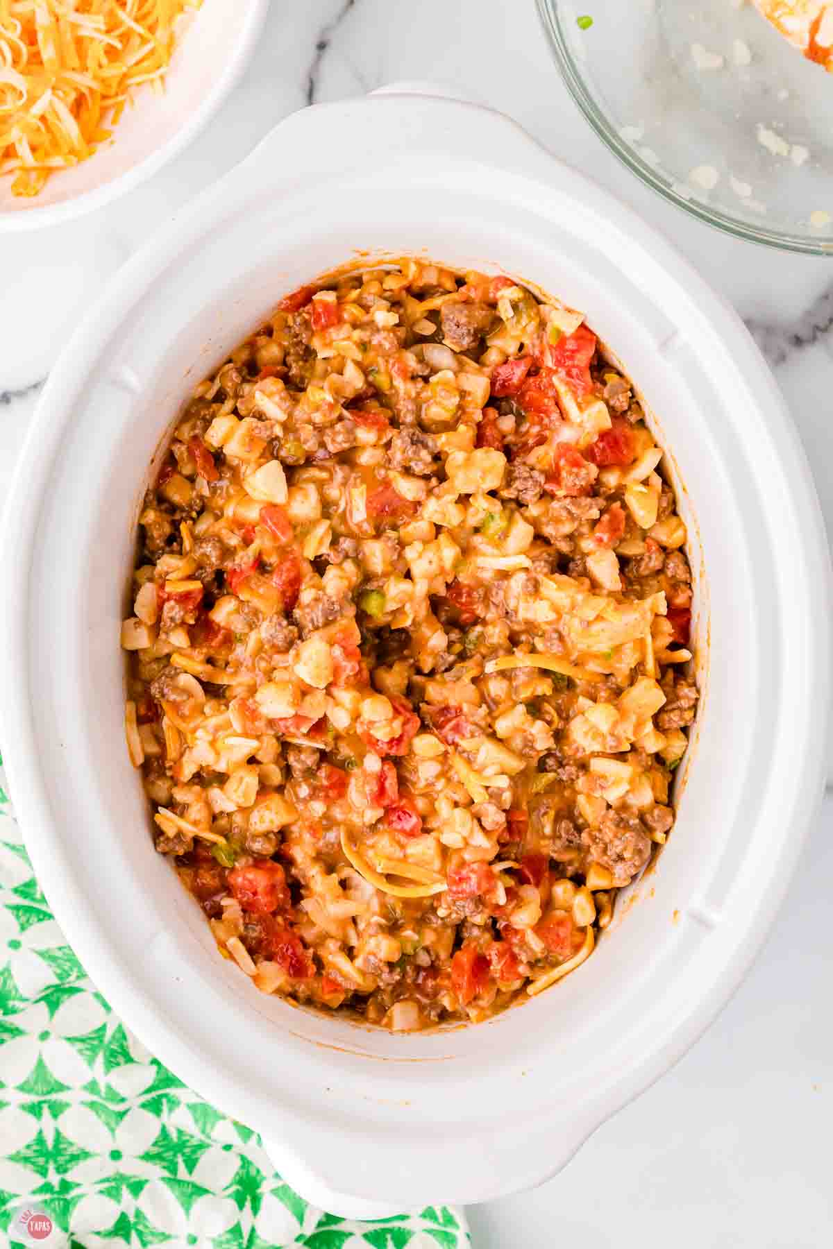 white crockpot insert filled with ground beef, potatoes, and sauce