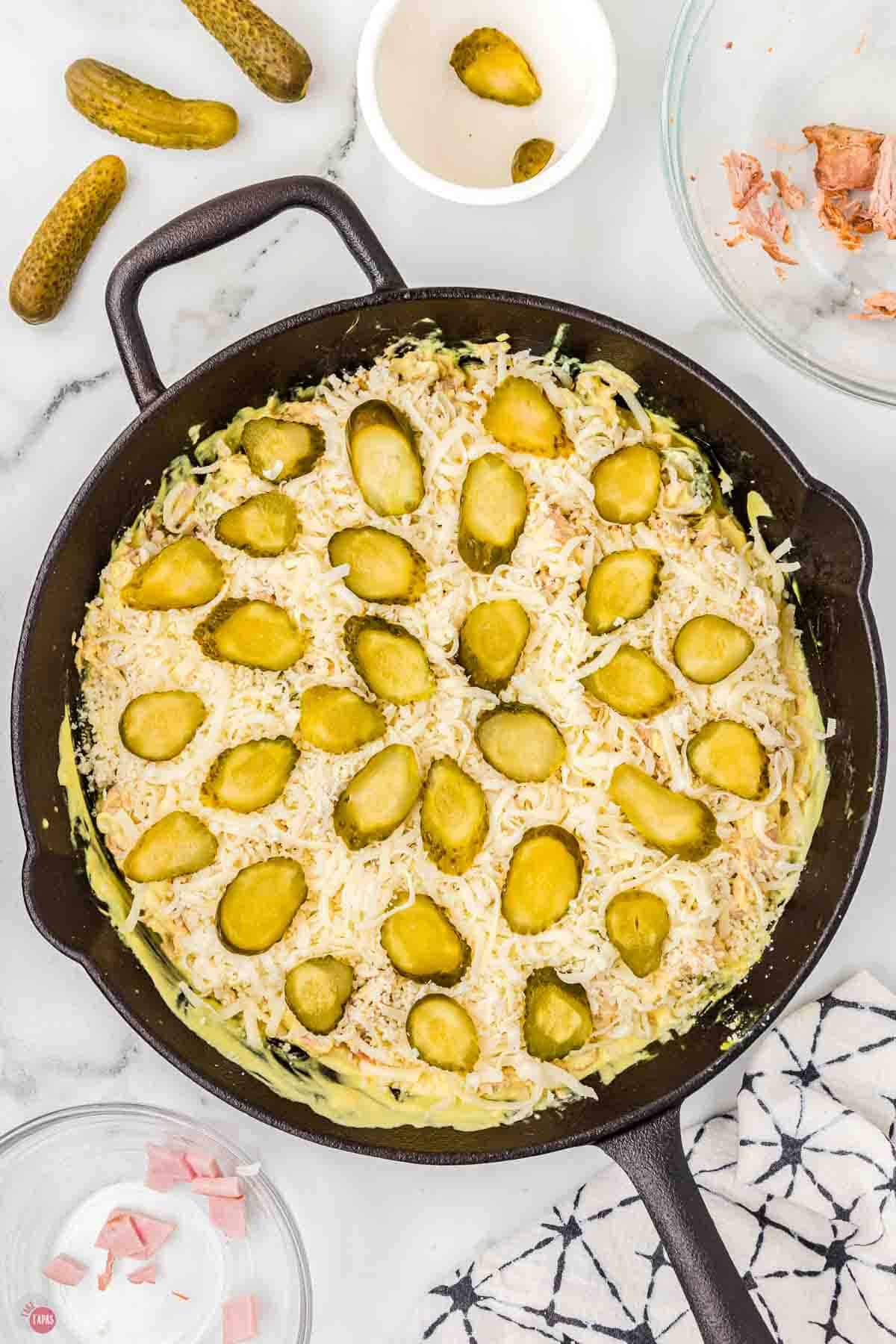 cast iron pan with cheese and pickles in it